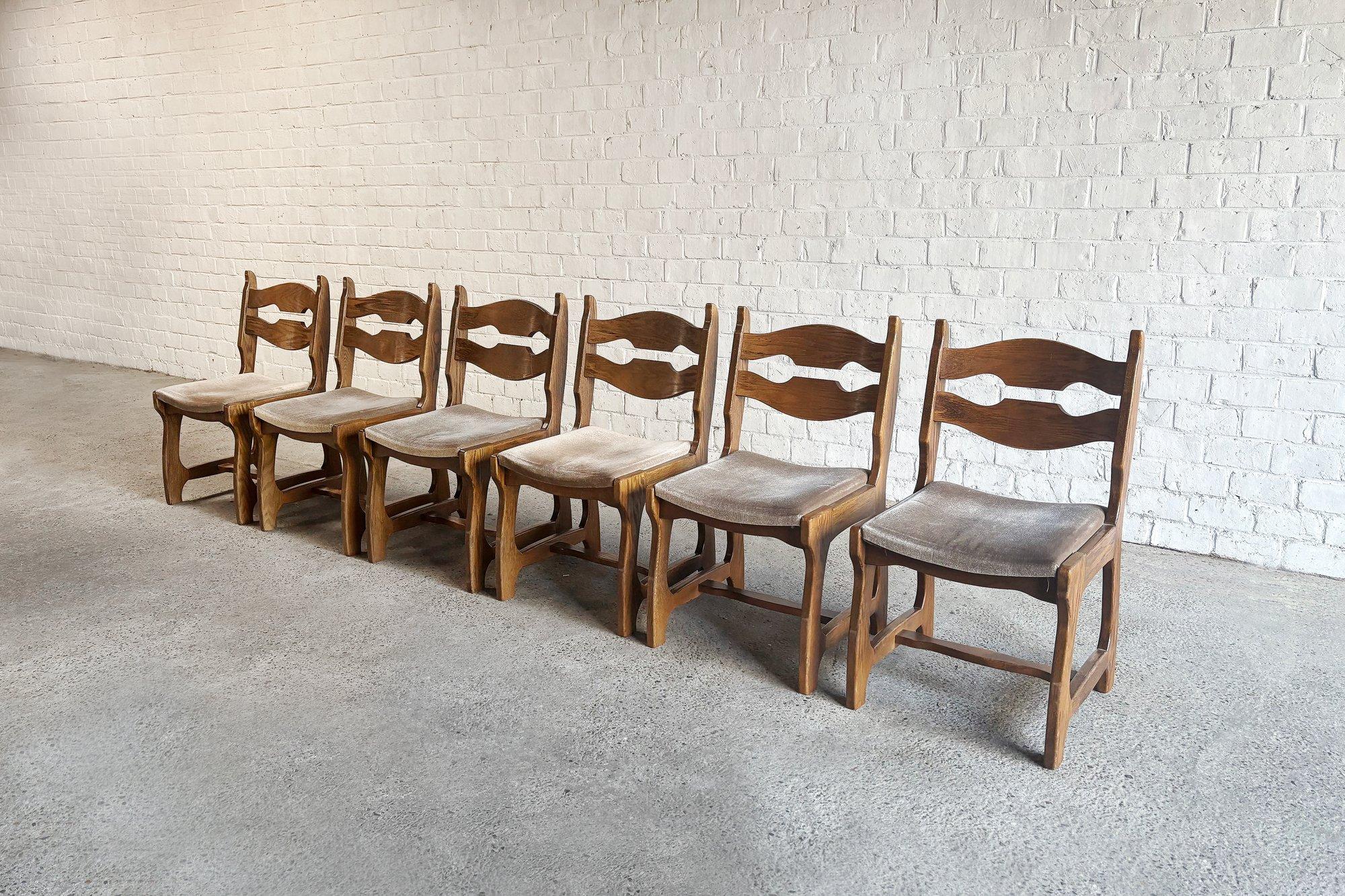Magnifique et inhabituel ensemble de 6 chaises en chêne massif conçues par Guillerme et Chambron pour Votre Maison, vers 1950. Sièges en velours beige d'origine. Ces chaises ont un aspect brutal et organique à la fois.