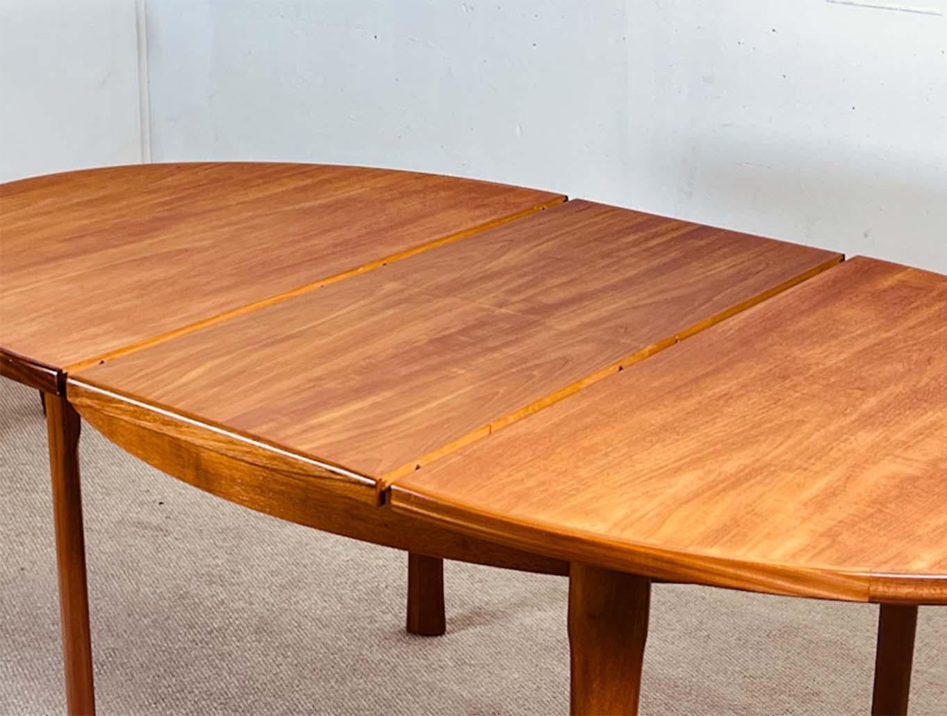 Mid-Century extending dining table with an oval shape and an internal extension.

The table is hand-crafted in a golden teak with a beautiful grain. The frame of the table is made in solid teak and the legs have a beautiful shape and can be