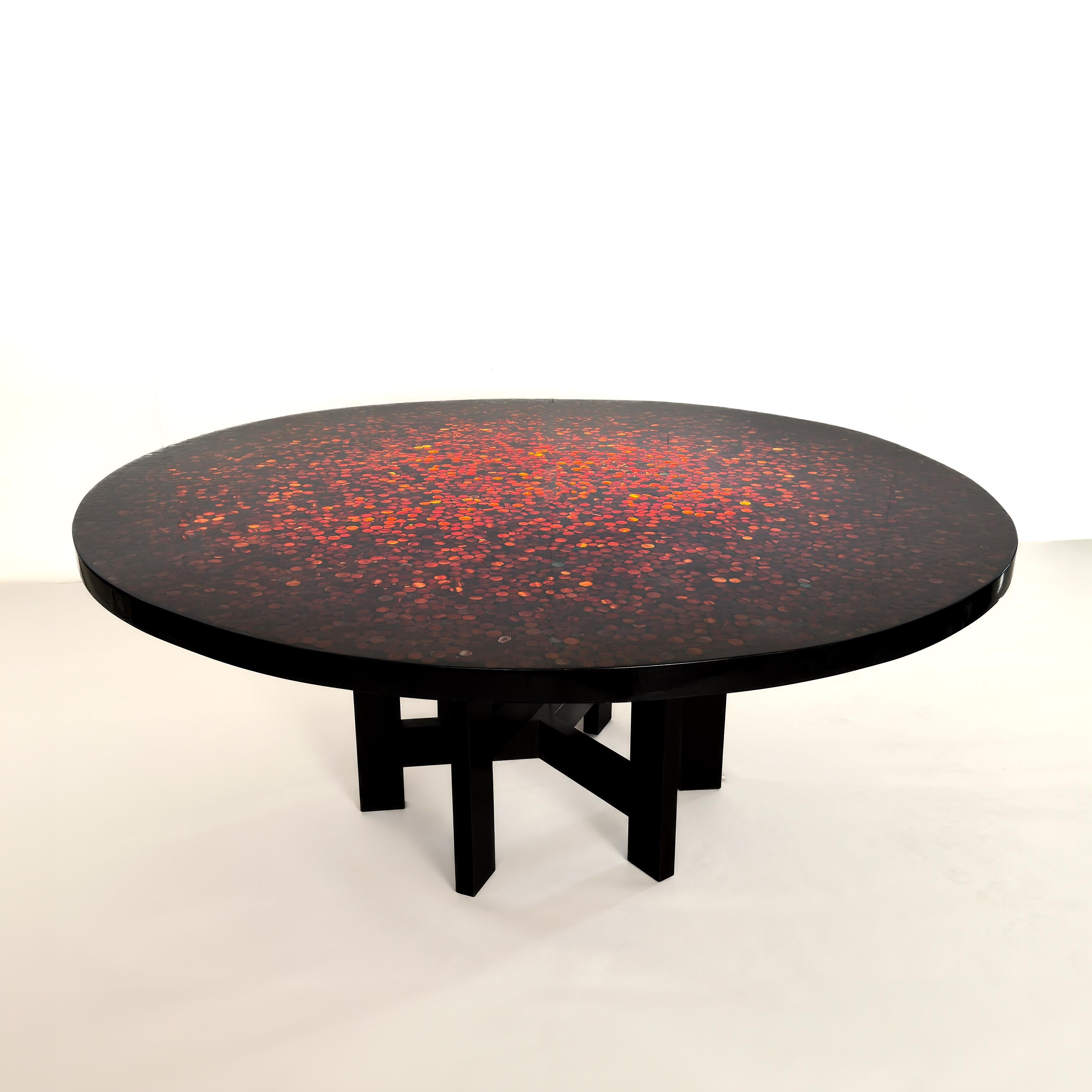 Dining or center table by Ado Chale.
Large dining table or center table with a resin top inlaid with Carnelian agate stones.
Equipped with a double tripod foot with wide spacer. (Six feet in total, two spacers), in wood.
The foot is part of the