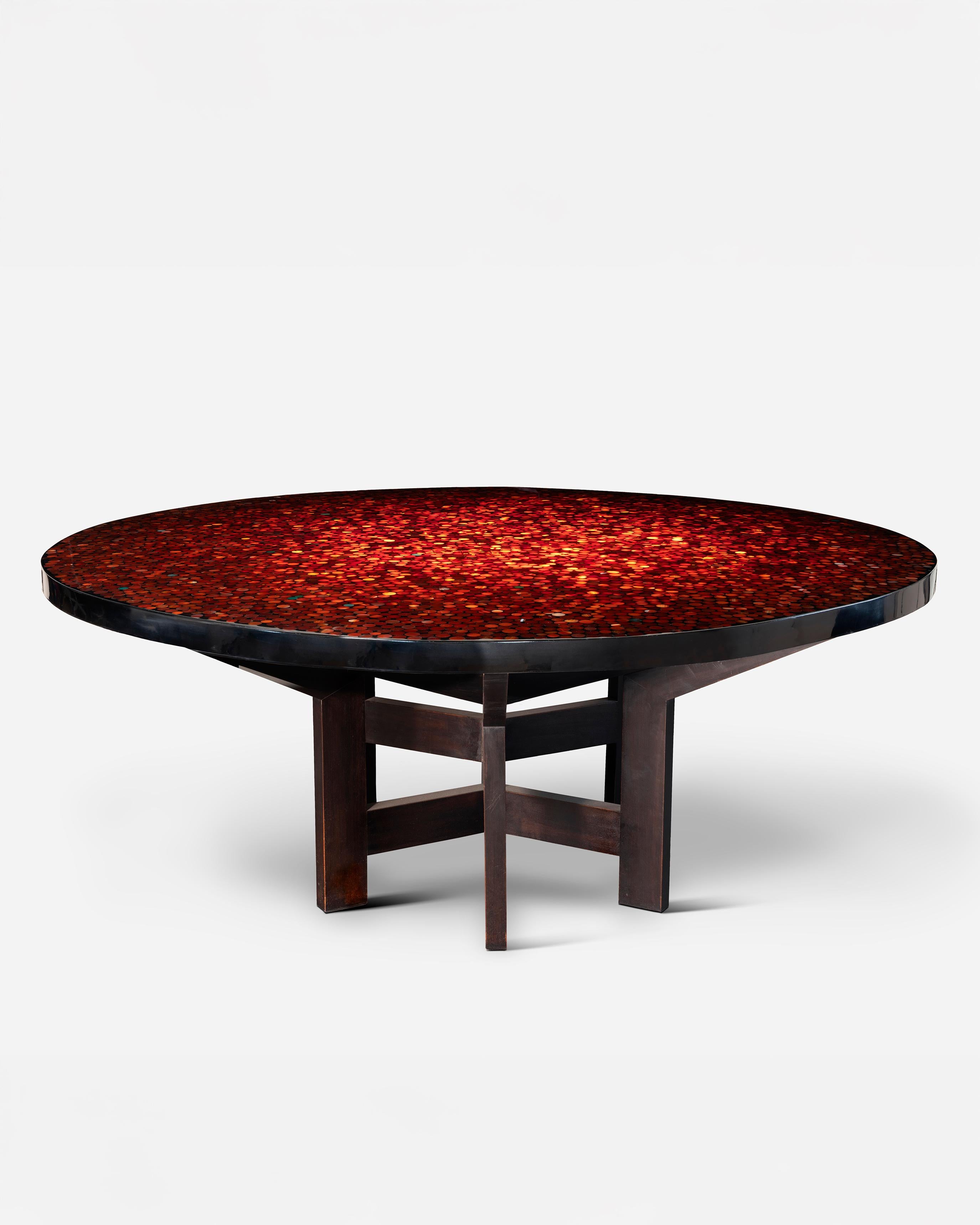 Dining or center table by Ado Chale.
Large dining table or center table with a resin top inlaid with Carnelian agate stones.
Equipped with a double tripod foot with wide spacer. (Six feet in total, two spacers), in wood.
The foot is part of the