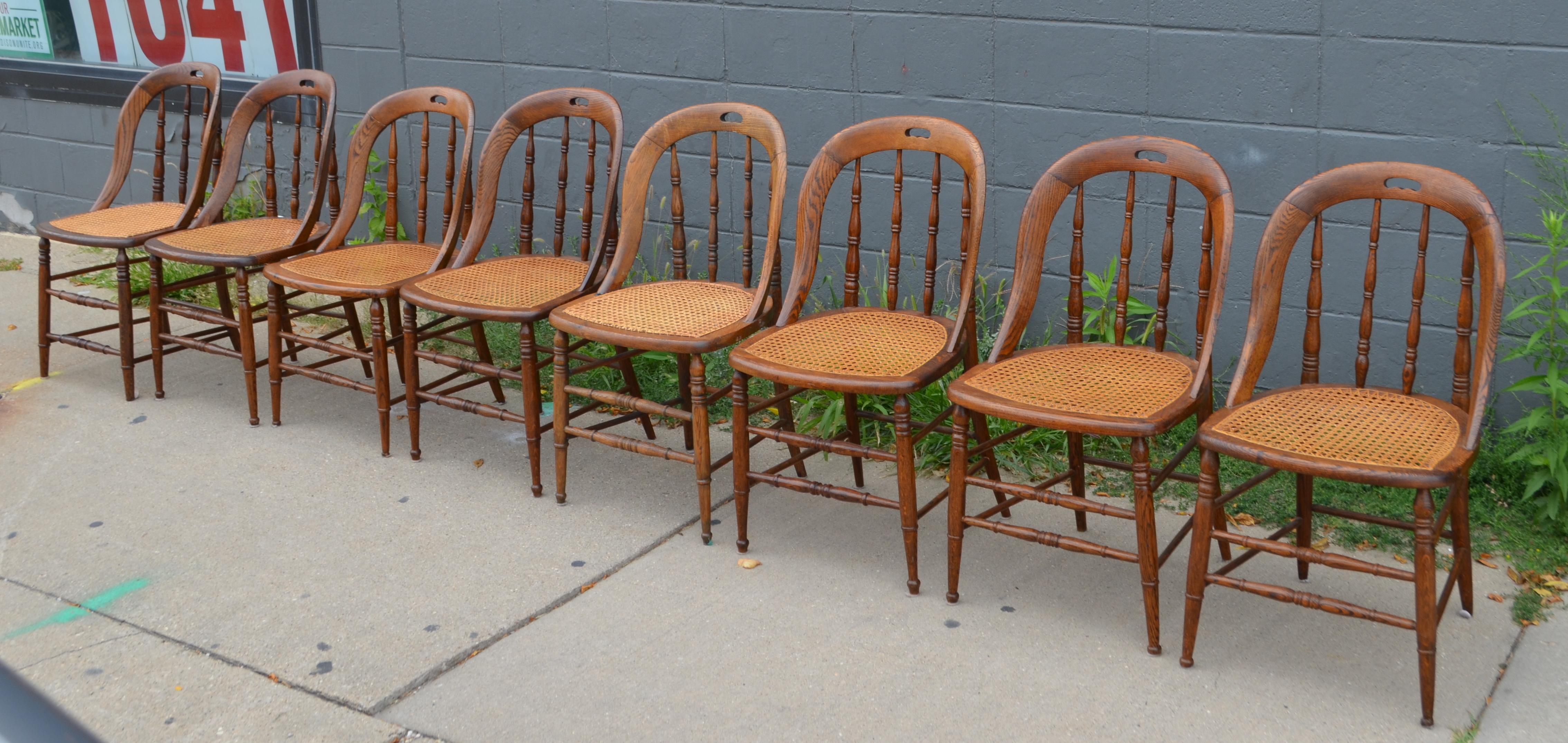 Dining room chairs, set of 8, with caned seats. Antique Windsor bow-back style in soft pine finish with cut-out handles. Lathe-turned legs and back spokes. Rare to find a large set of 8 in such excellent antique condition. Very comfortable and