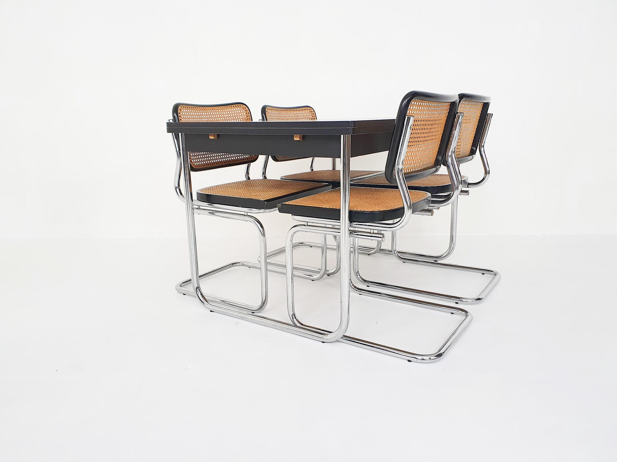 Four tubular chrome dining chairs with webbing seating and back.
The table has chrome feet and black wooden top with two extension leaves. Some small repairs on the side of the table.
Measures: Chairs:
Width: 45 cm
Depth: 50 cm
Height: 82
