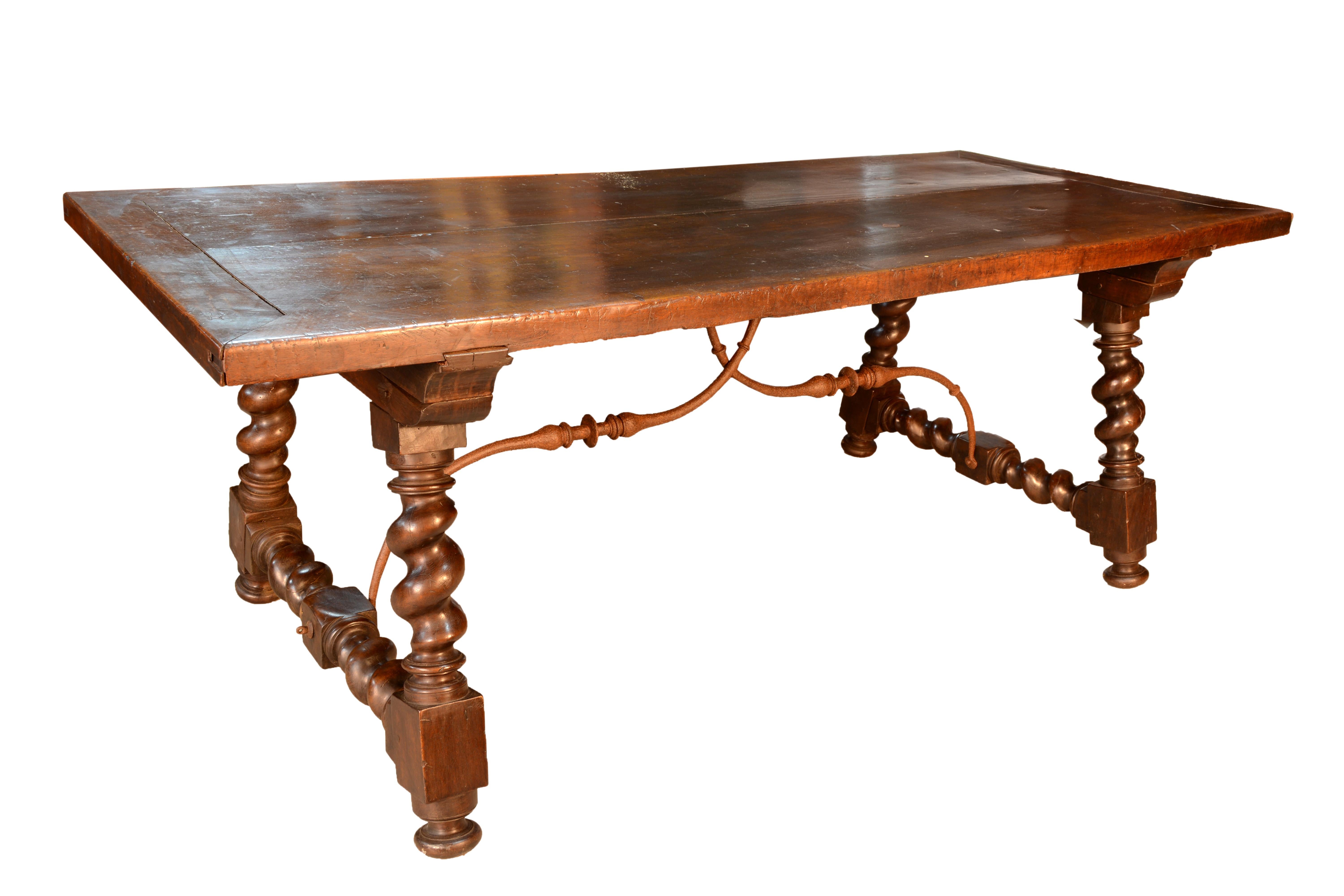 Dining table with two-piece header board on legs with Solomonic turning and chamfer attached to it with curved wrought iron fasteners, following Baroque models