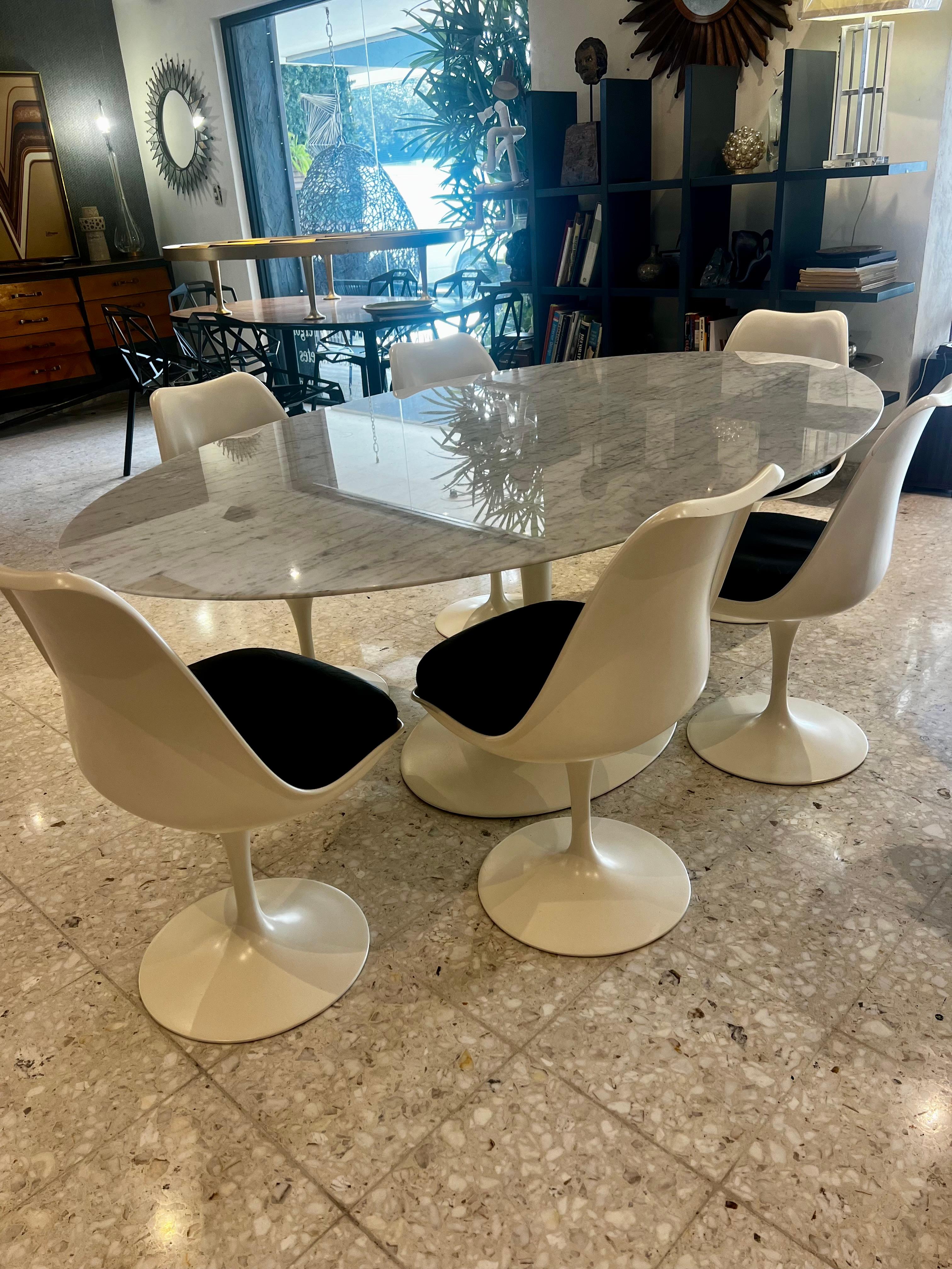 Ovaler Tisch aus Carrara-Marmor mit sechs armlosen Tulpenstühlen, die mit echtem schwarzem Leder bezogen sind.