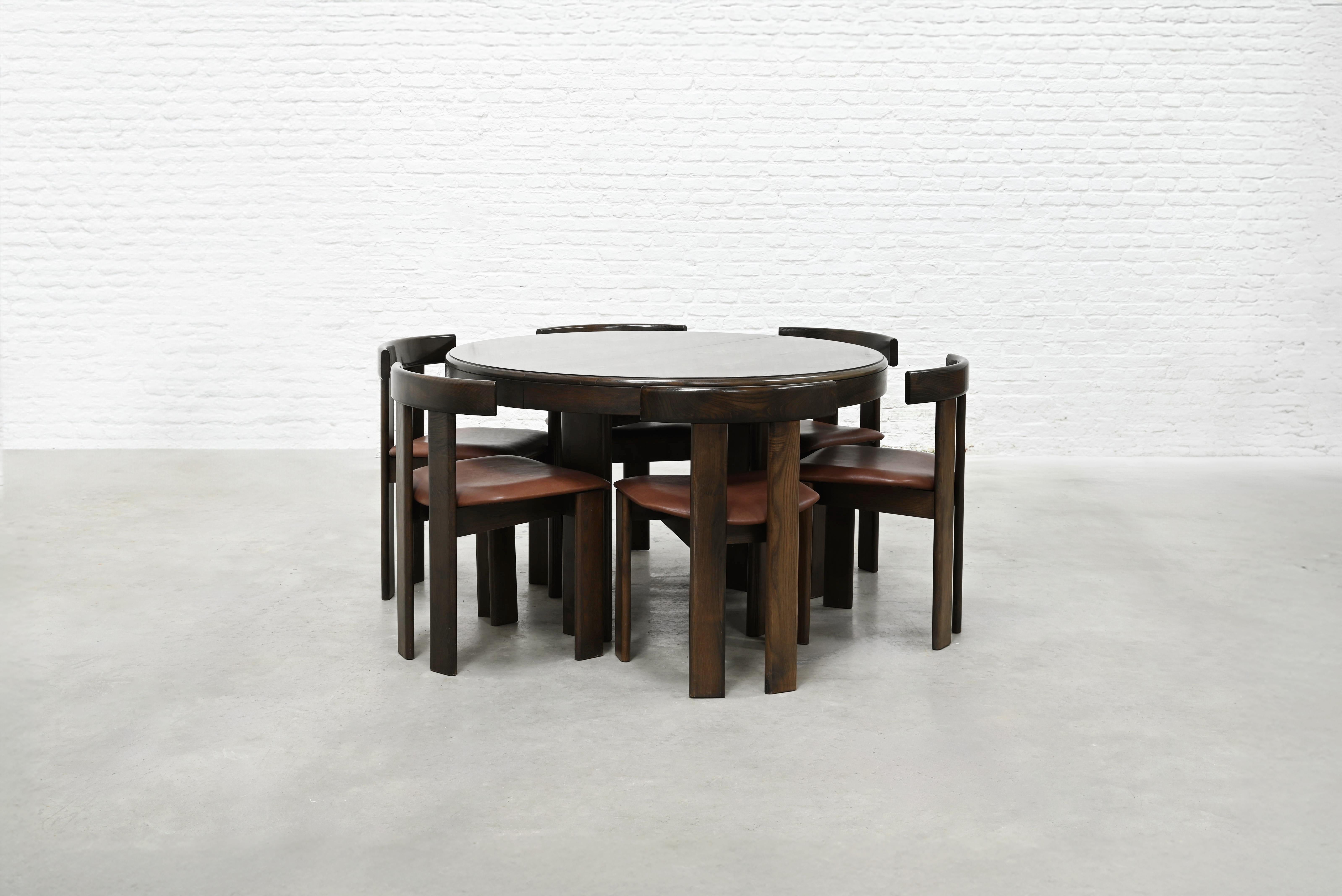 A characteristic 1960’s Italian dining set by Luigi Vaghi for Former. The round ash wood dining table features a smooth, dark-toned top with a sturdy, segmented base, reflecting the designer's emphasis on organic form. The table is extendable with a