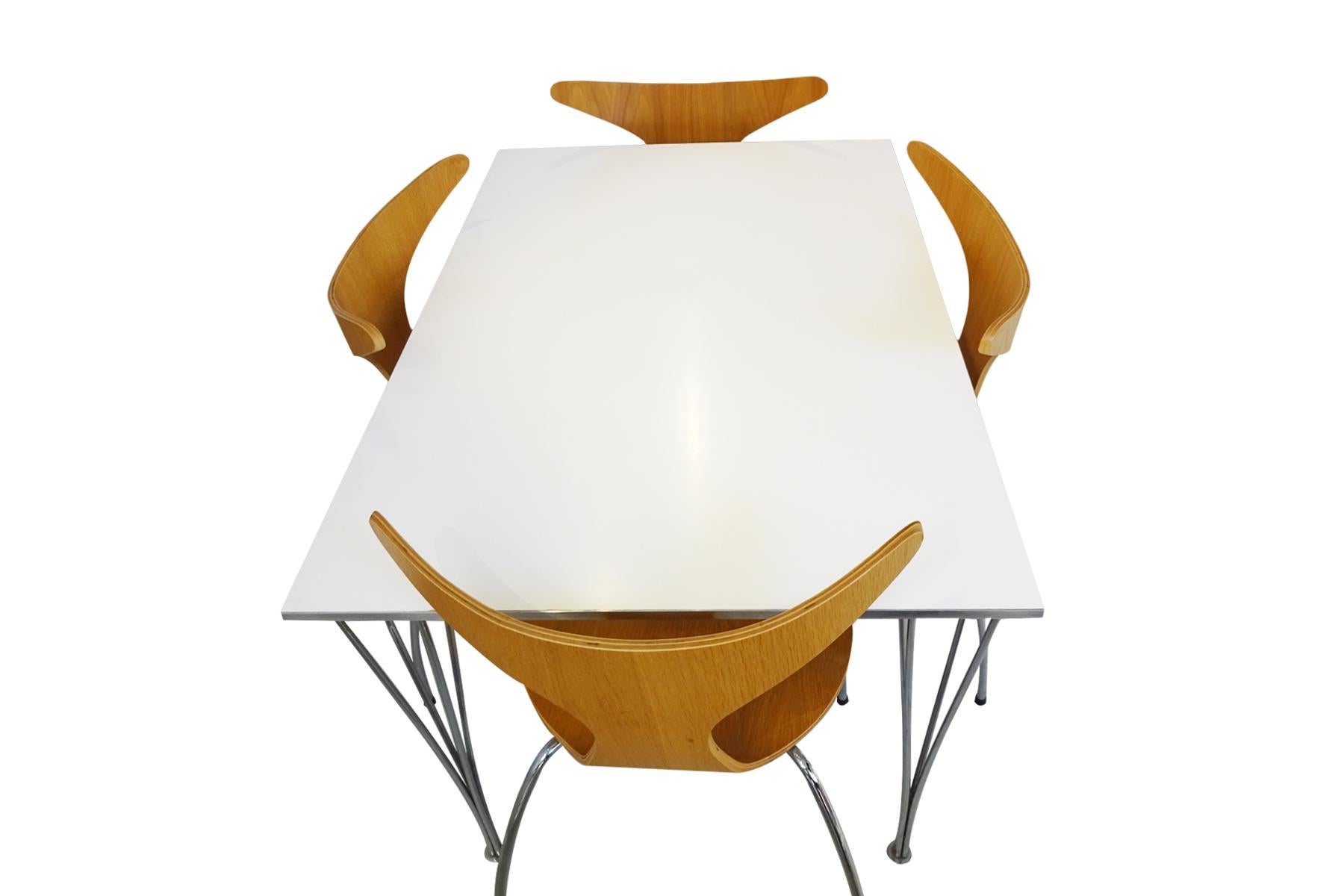 A Mid century 1960s designed white and silver rectangular dining table designed by Piet Hein, Arne Jacobsen and Bruno Mathsson manufactured by Fritz Hansen in 1989 and a set of Danish designed Danform ‘Dolphin’ stacking chairs in oak veneer and
