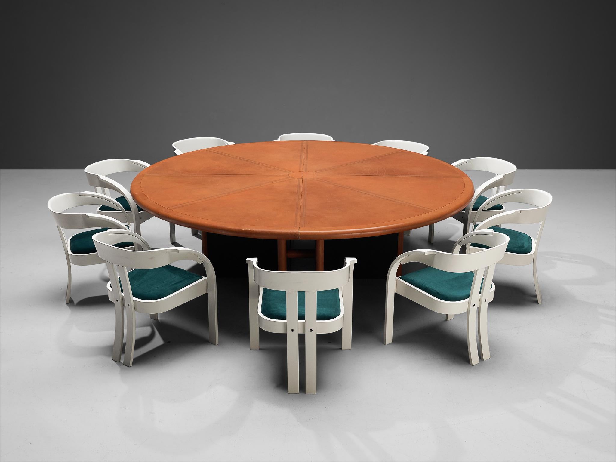 Guido Faleschini for i4 Mariani, dining or conference table, leather, wood, metal, Italy, 1970s, with Giovanni Battista Bassi for Poltronova, set of ten armchairs model 'Elisa', velvet, lacquered beech, Italy, 1960s 

This massive round dining