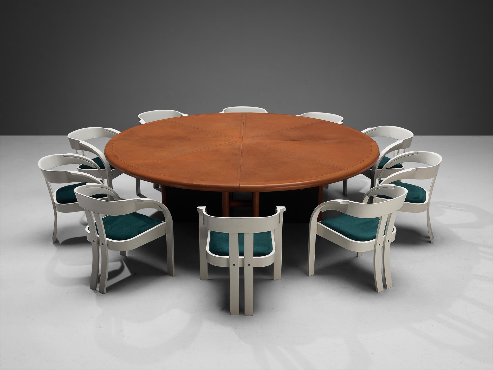 Guido Faleschini for i4 Mariani, dining or conference table, leather, wood, metal, Italy, 1970s, with Giovanni Battista Bassi for Poltronova, set of ten armchairs model 'Elisa', velvet, lacquered beech, Italy, 1960s 

This massive round dining table