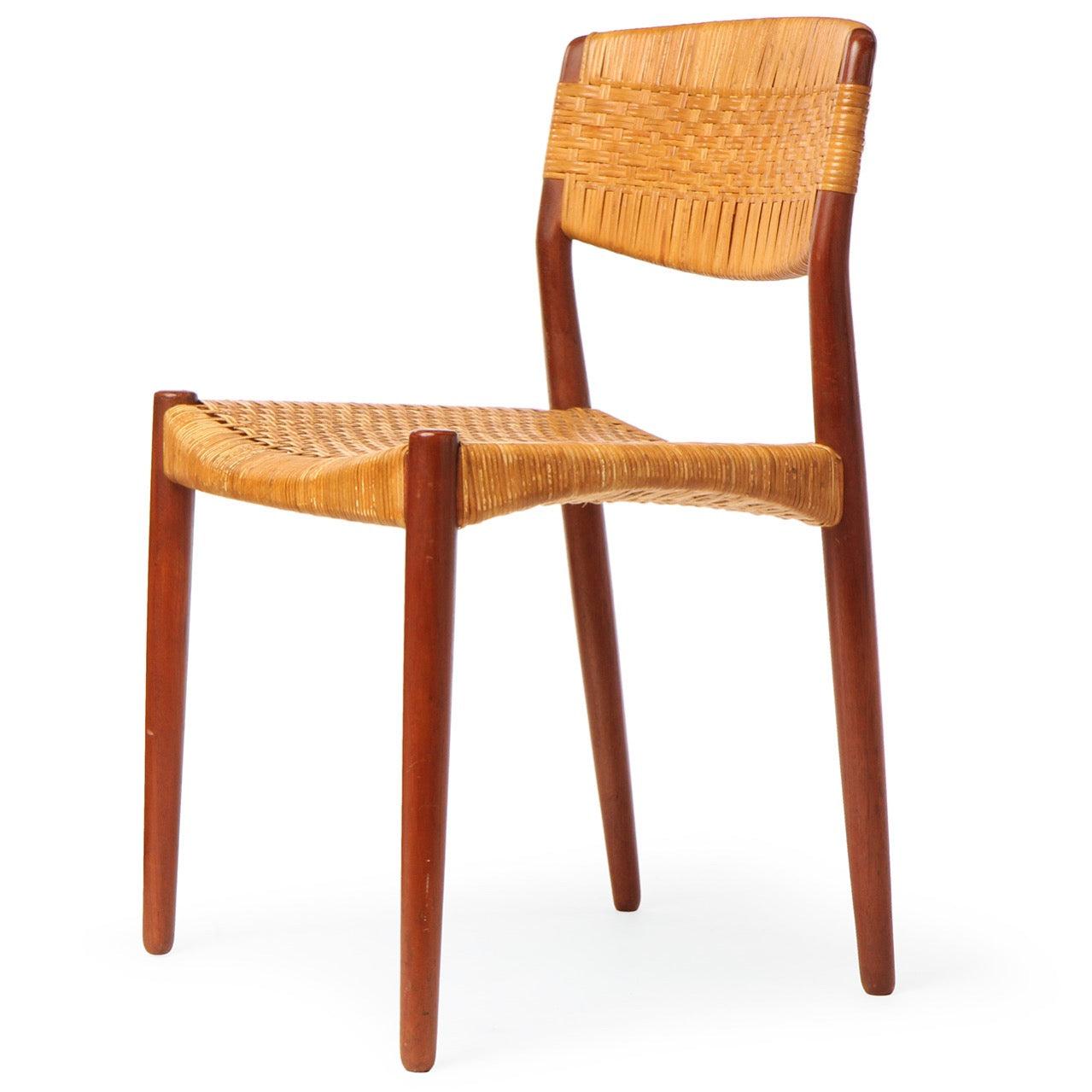 A dining side chair with a teak frame and hand woven cane seat and back.