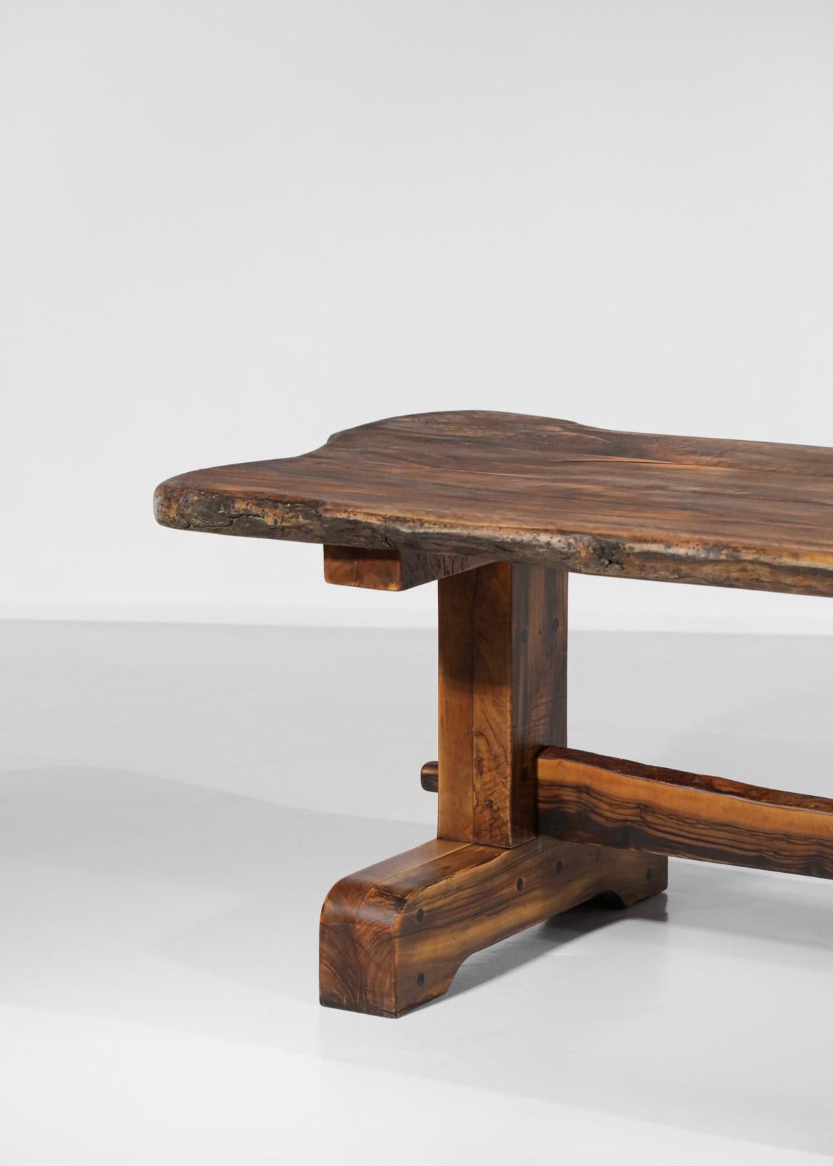 Magnifique et imposante table de salle à manger et ses deux bancs des années 60. Structure en bois d'olivier massif. Les deux bancs sont sculptés dans une seule pièce de bois et le plateau de la table repose sur deux pieds massifs reliés par une
