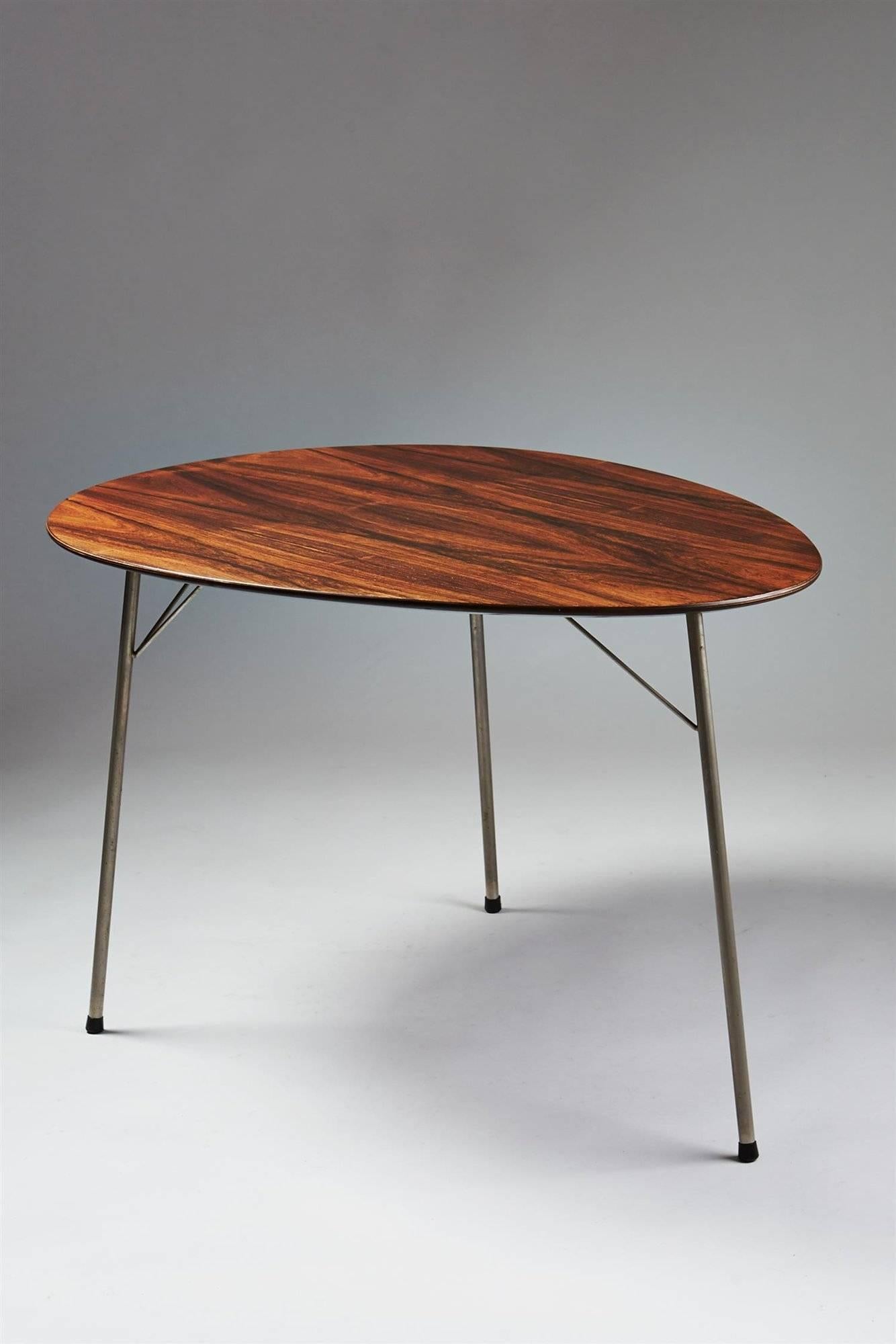 Dining table and four chairs, designed by Arne Jacobsen for Fritz Hansen, Denmark, 1965.
Rosewood and stainless steel.

Dimensions of the table:
H 69 cm/ 27 1/4