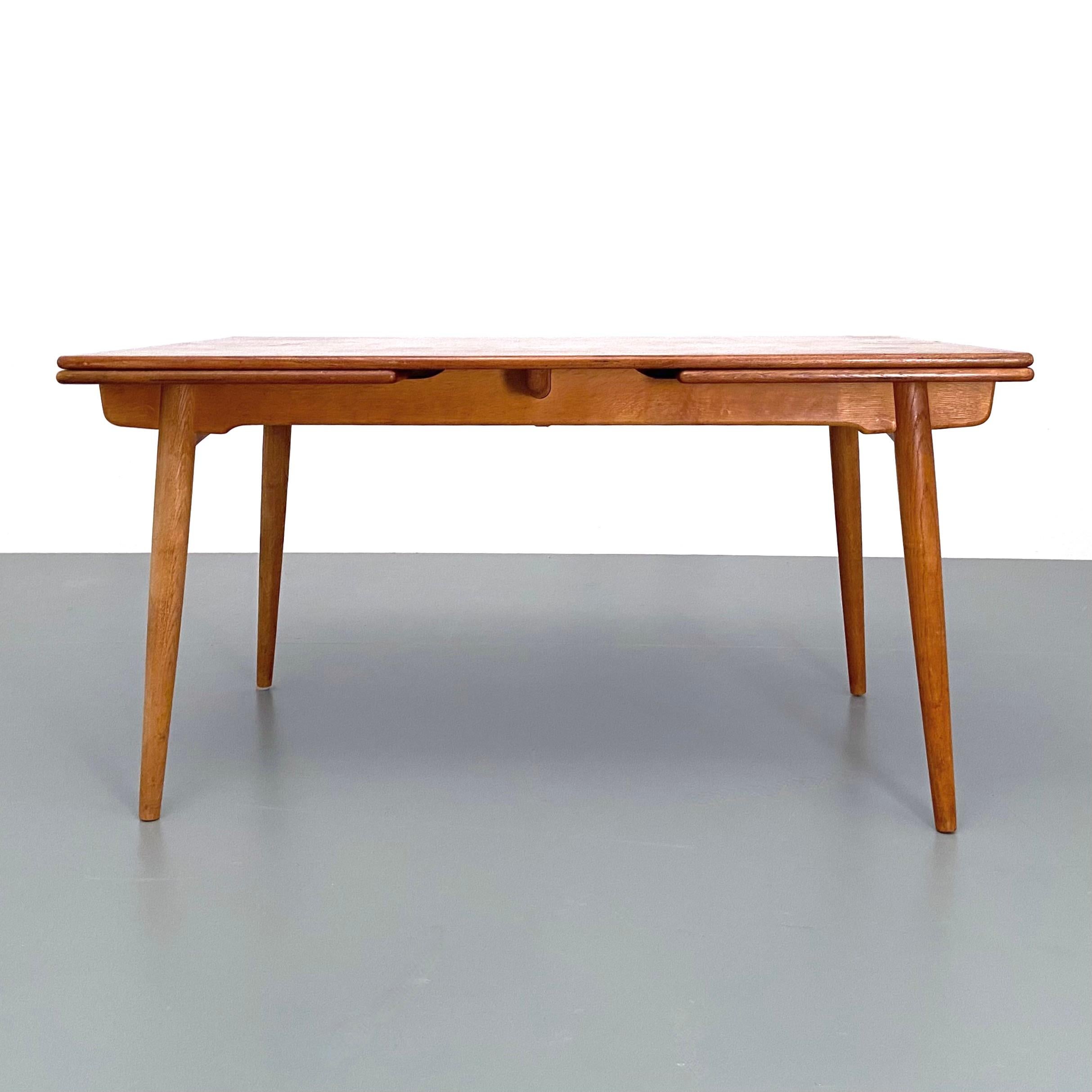Esstisch Modell AT-312, entworfen von Hans Wegner für Andreas Tuck, Dänemark, 1960er Jahre.
Der aus Eiche gefertigte Tisch verfügt über zwei ausziehbare Platten, die sich unter der Tischplatte verbergen und sich schön in diese integrieren, wenn der