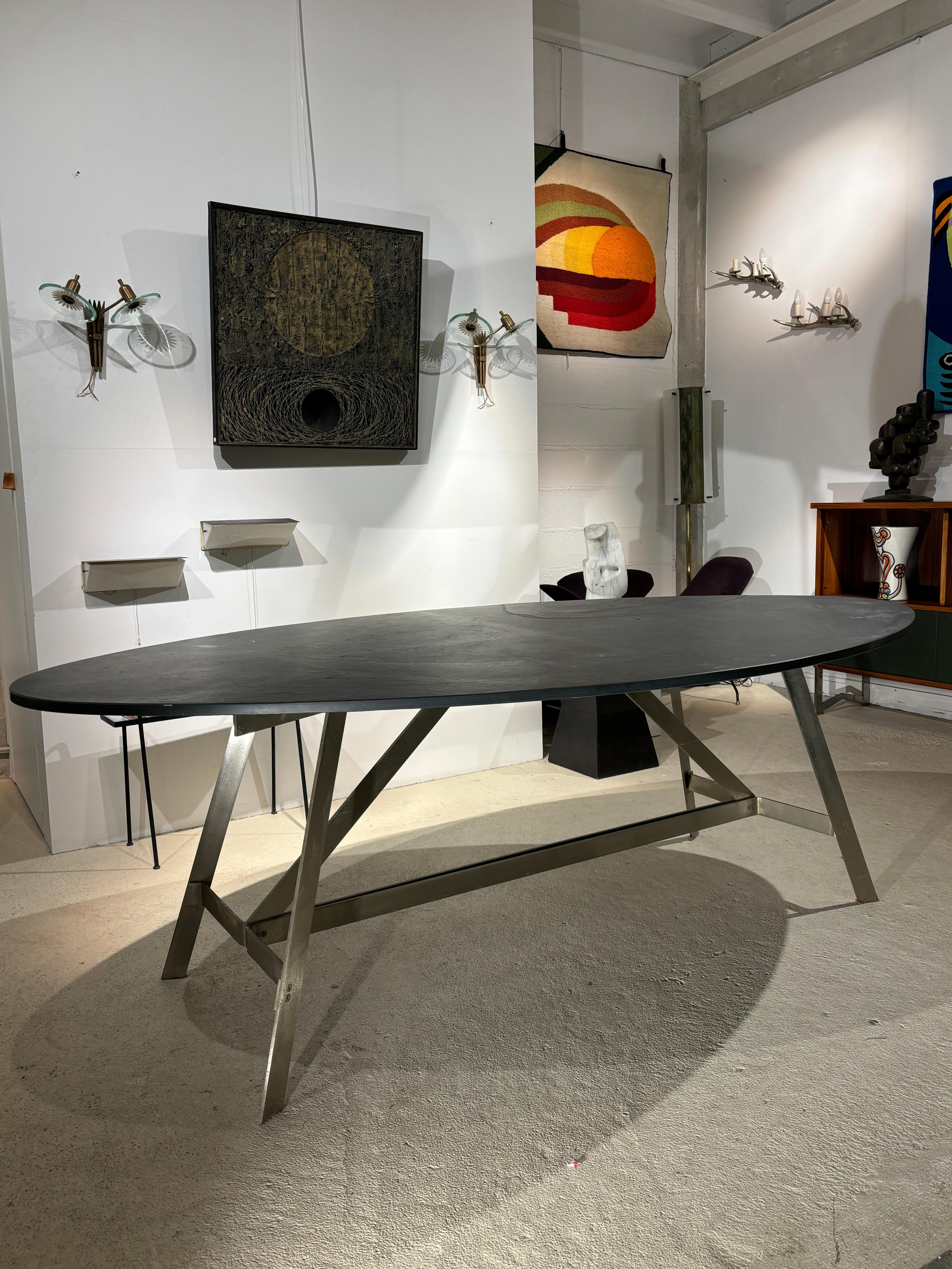 Jolie table à diner attribuée à Françoise See avec un plateau oblong en ardoise épaisse. 
Le piétement possède une forme g�éométrique interessante, la rouille n’est qu’en surface. 