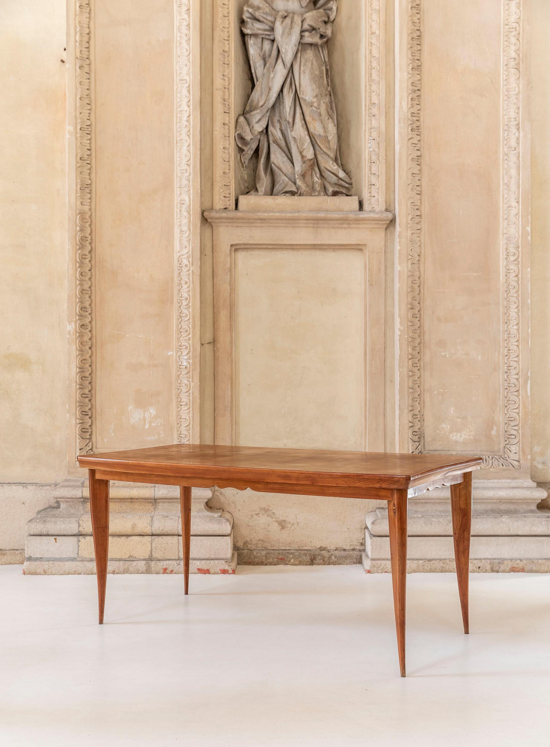 Dining table attributed to Paola Buffa in cherry wood.
The four legs are shaped and slender. The top has a concave shape along the short sides and a classy decoration motif below the slightly curve outwards long sides.
  