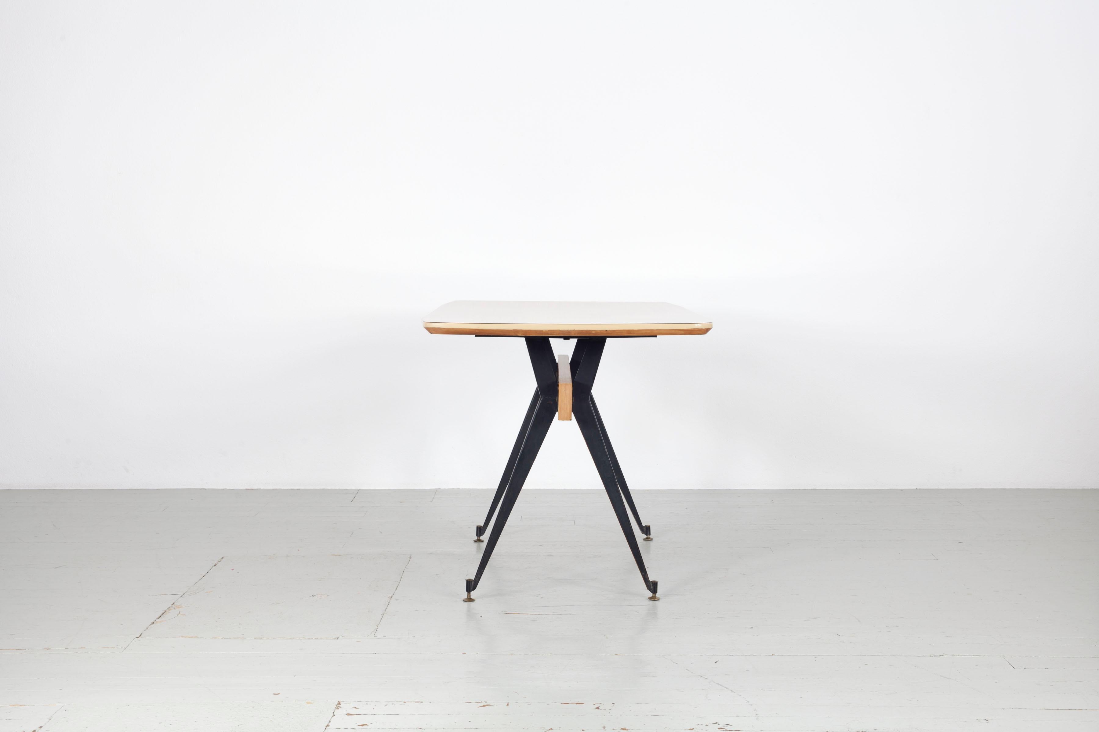 Dieser italienische Esstisch wurde von Carlo Ratti in den 1950er Jahren entworfen. Der Tisch wurde in Mailand von der Firma Industria Legni Curvati hergestellt.  Die hölzernen Tischbeine sind mit dunklem Eisen ummantelt und stehen auf verstellbaren