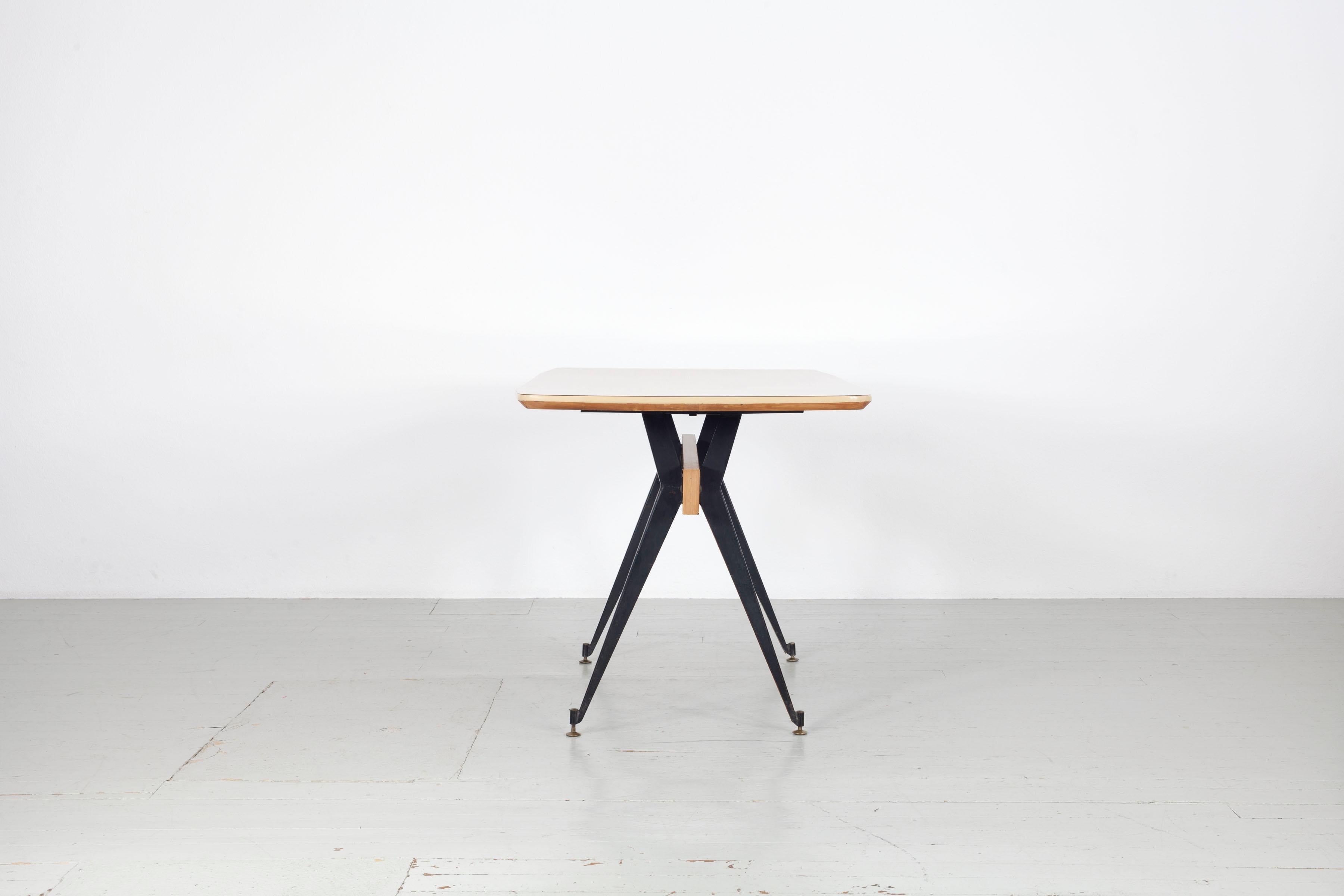 This Italian dining table was designed by Carlo Ratti in the 1950s. The table was manufactured in Milan by the company Industria Legni Curvati.  The wooden table legs are encased in dark iron and stand on adjustable brass finials. Apart from minor