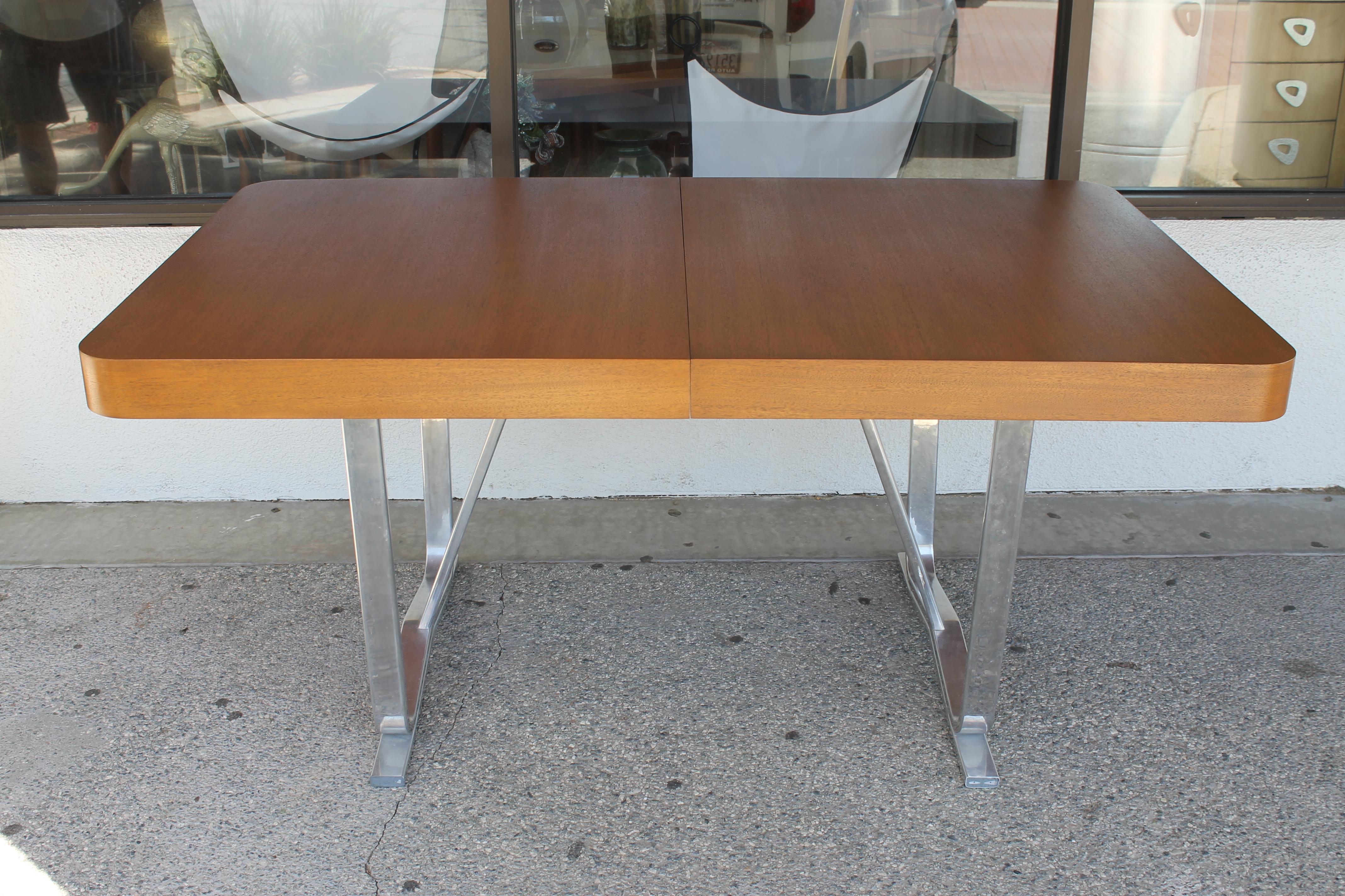Dining table on aircraft aluminum frame base by the Cessna Aircraft Company. It says it's a Buckskin finish which reminds us of mahogany. Measures: 64.25