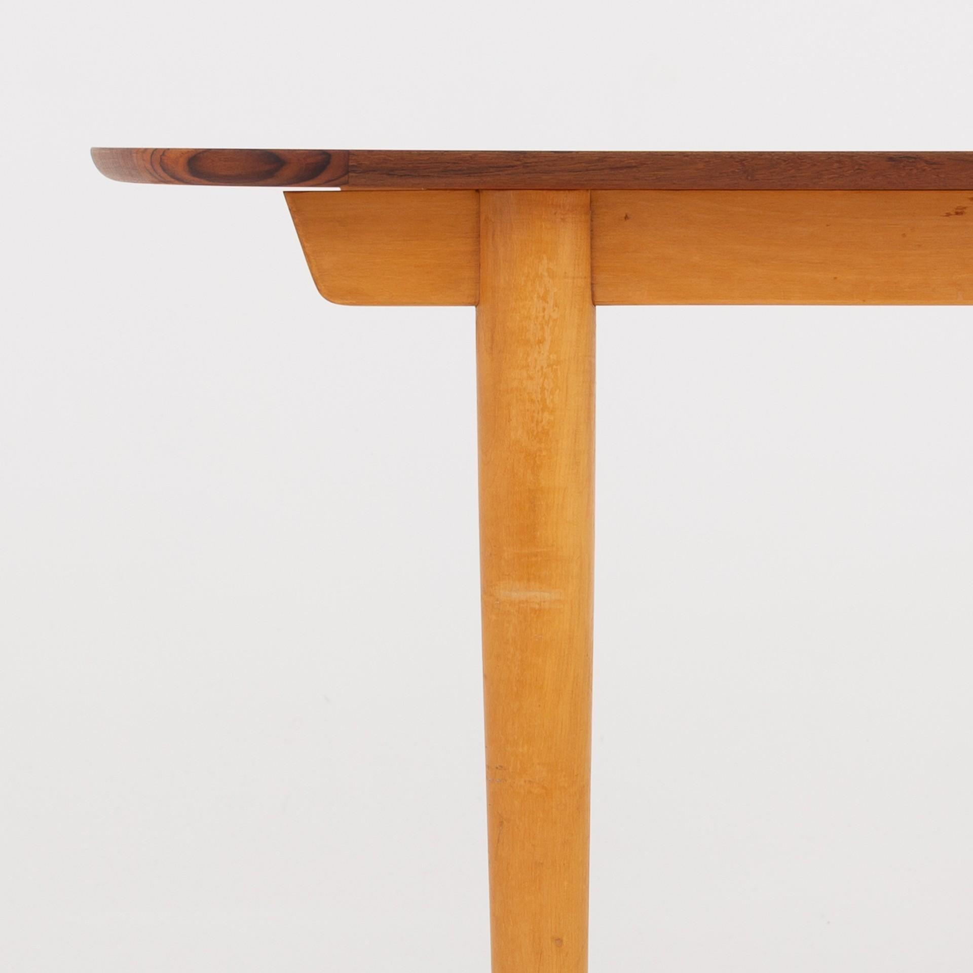 Dining table with extension, table top in teak, legs in beech and shoes in teak. Storage for extension underneath table top. Two leaves of 41 cm. per piece. Maker Søren Willadsen.