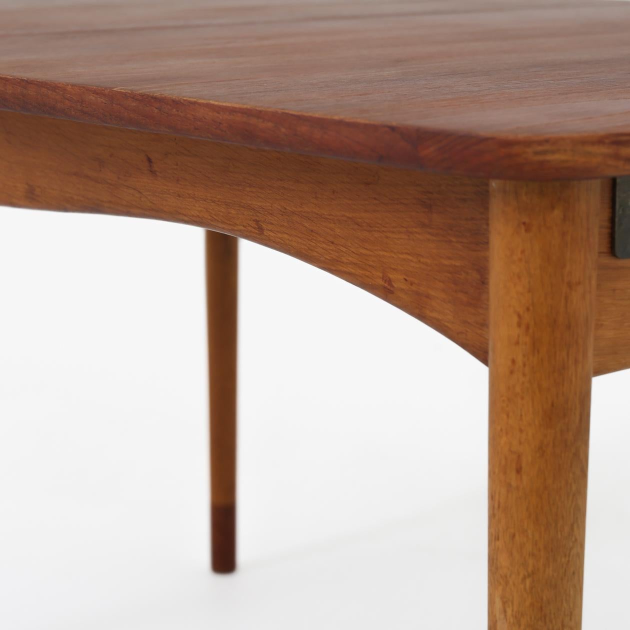 Dining table with teak top and oak frame and shoes of teak. Two additional teak plates of 48 cm included. Max. L. 232 cm. Finn Juhl / Bovirke.