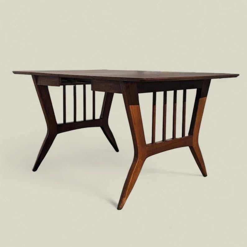 Cette table de salle à manger de Garrison Furniture Co. est dotée d'un plateau en stratifié durable et d'une base en bois élégante, parfaite pour toute cuisine. Le design du milieu du siècle ajoute une touche de charme rétro à n'importe quel