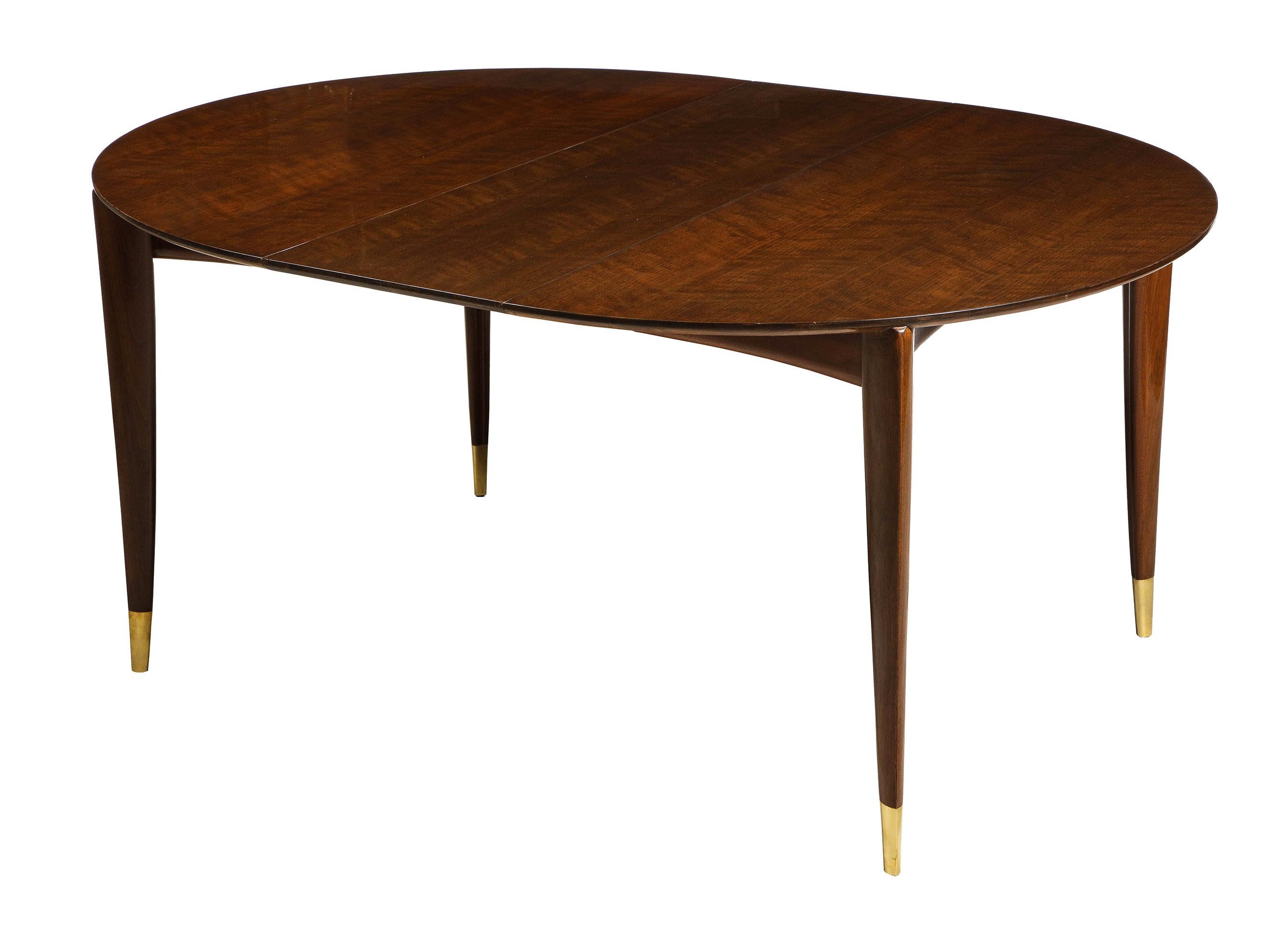 Having a lovely lacquer finish, the walnut dining table for M. Singer and Sons, starts as a round breakfast size table and expands to accommodate 10-12 chairs. The lovely grained top over a slightly concave apron. With 4 tapered legs with brass