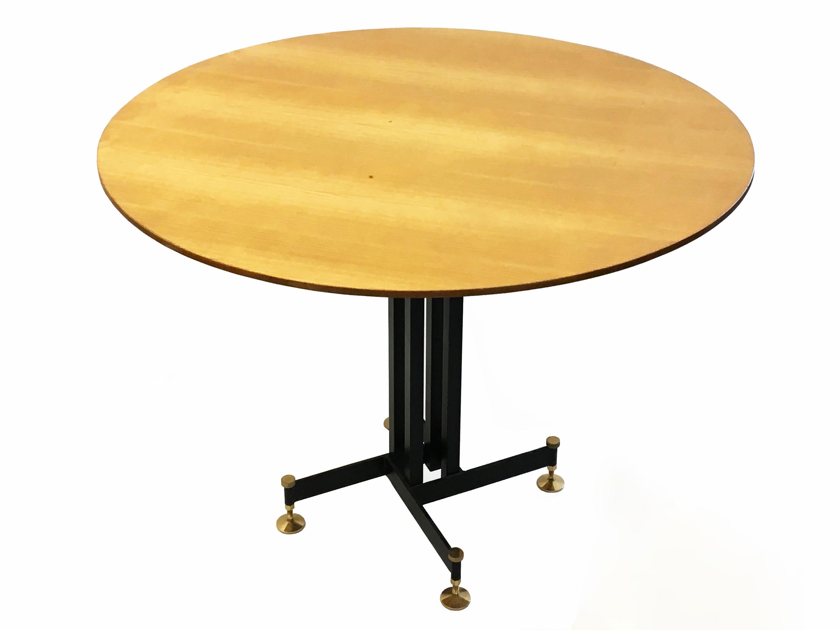 Italian dining table attributed to Ignazio Gardella comprises a black enameled steel base with brass feet that can adjust up to 2 inches (5 cm) for height and leveling purposes, that supports a round wooden top.