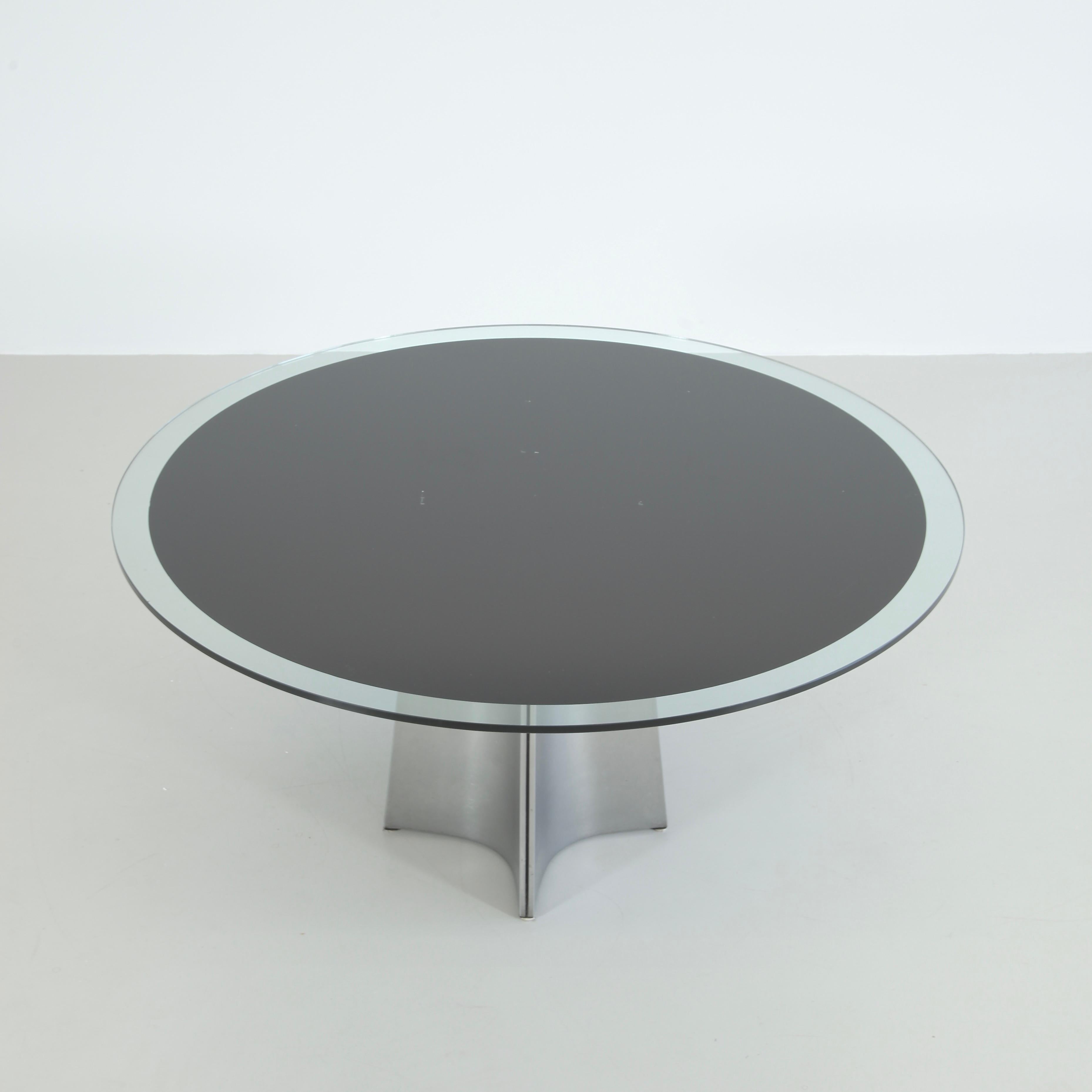 Round pedestal dining table designed by Luigi Saccardo. Italy, ARRMET, circa 1973.

Brushed aluminum base and the original round glass top with black center underlay. The curved metal producing a star-base. An iconic piece by the Italian Modernist