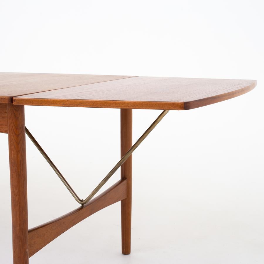 Dining table in teak and oak with two leaves, held by a turnable brass bracket. Unknown maker.
Measures: Length 130.00cm, additional length 232.00cm.