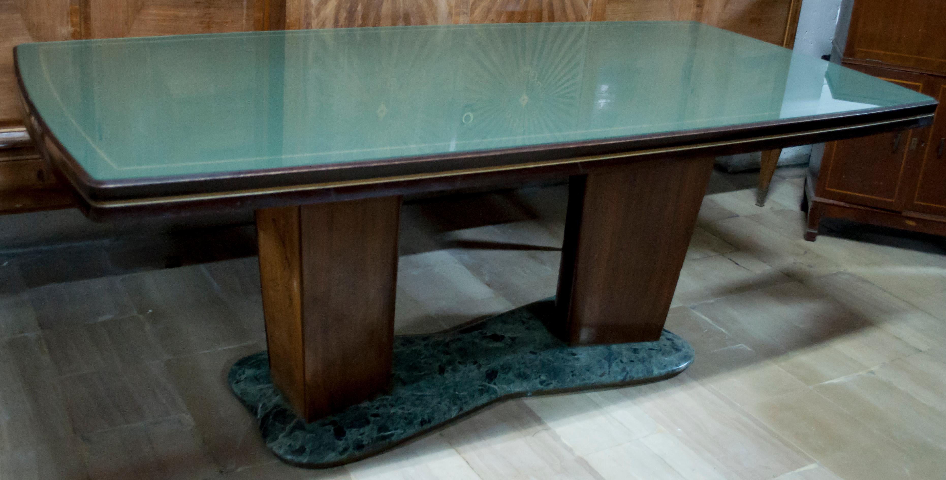 This table was designed by the famous Italian design Vittorio Dassi, Italy 1950, the table has a rectangular green glass top, the top is supported by two large bases in rosewood and maple, the bases are carved in relief, resting on a base of green