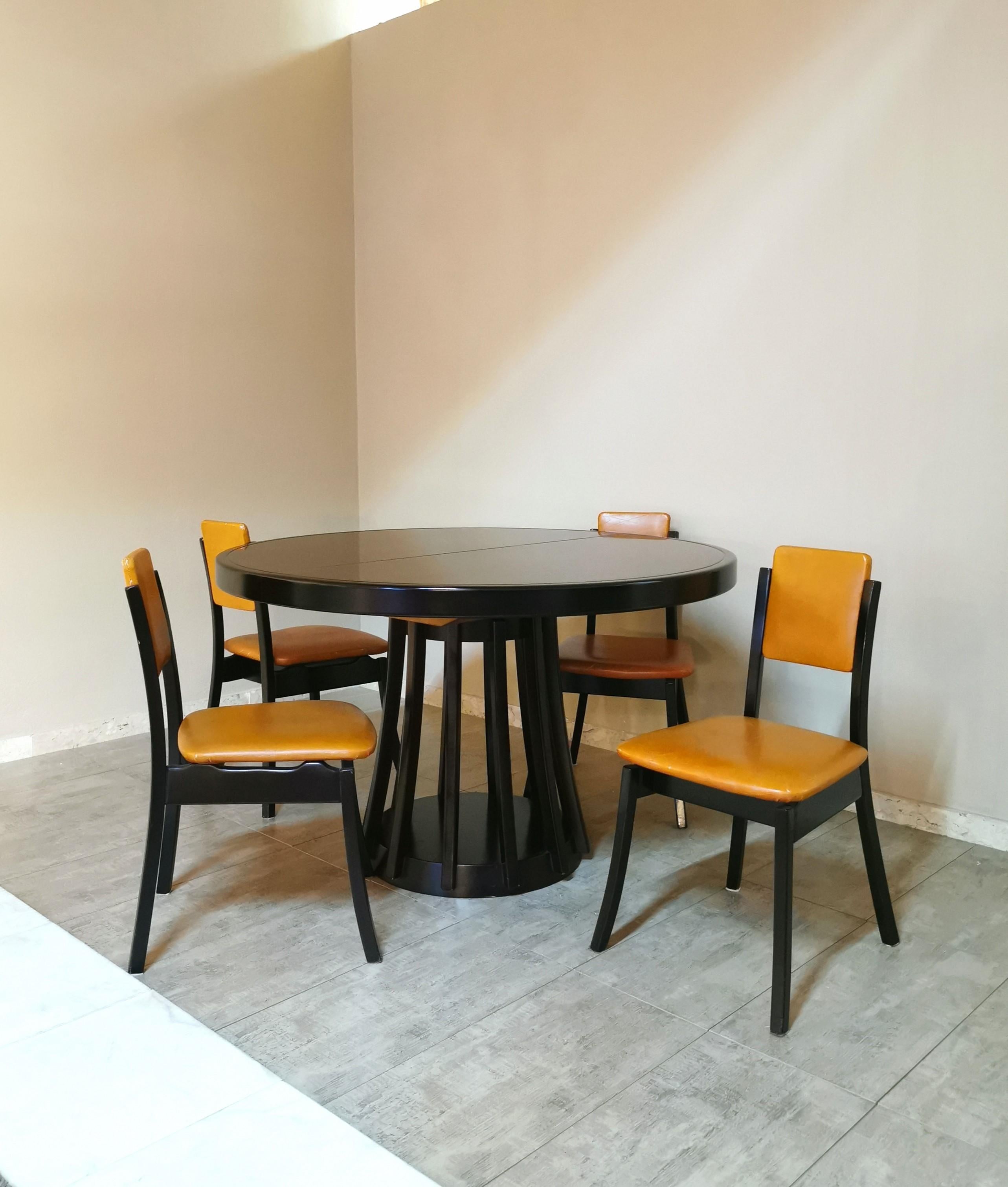 Coordinated set of 4 dining chairs and 1 table designed by the renowned Italian designer Angelo Mangiarotti in the 70s. The chairs have a dark-toned wooden structure with particular legs that curve outwards. The seat and back are covered in