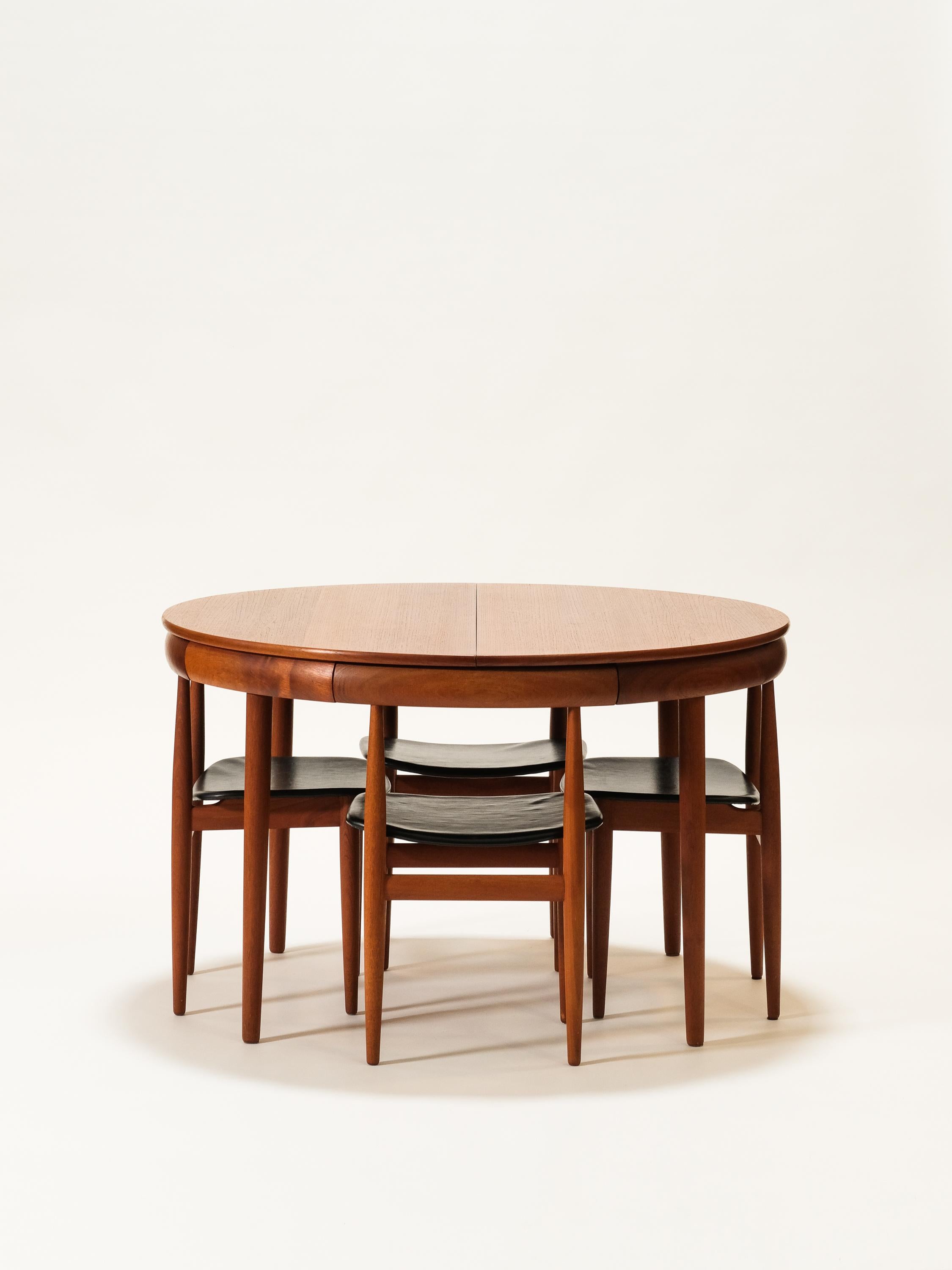 Unique “Roundette” dining set designed by Hans Olsen for Frem Rølje in Denmark circa 1960s. This striking dining set features a teak wood round table and four dining chairs. The dining chairs seamlessly tuck into the table with their curved back