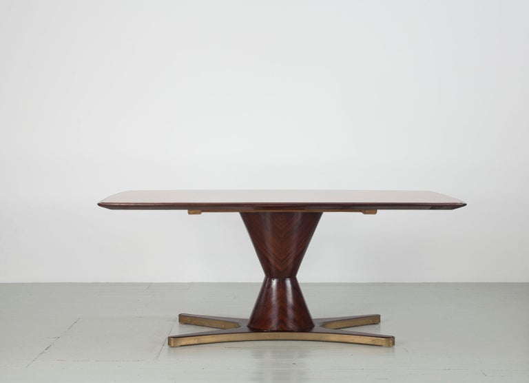 

This dining table was designed by Vittorio Dassi in Italy in the 1950s. The table frame is made of rosewood and an antique pink glass top is set into the top of the table. The unusual and sturdy central leg stands on a rosewood base framed with