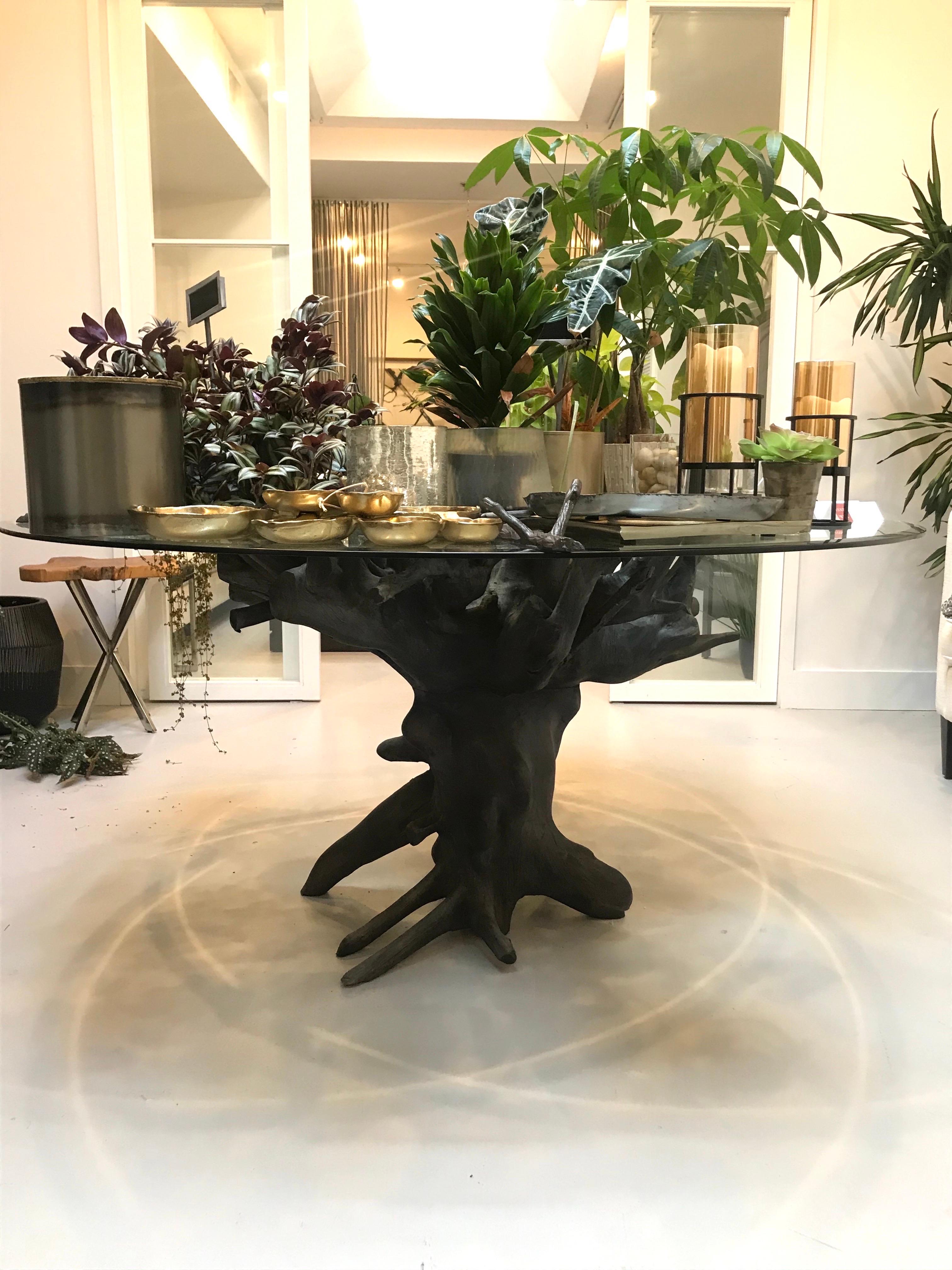 Round Organic Modern dining table in reclaimed teak root wood with large glass top. The natural root base has been charred to create its unique charcoal finish. Stunningly beautiful from every angle, featuring a trunk base with extended branches.