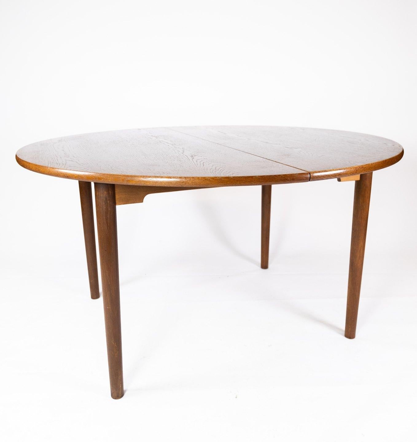 This Danish-designed dining table from the 1960s exudes a timeless appeal with its elegant silhouette and rich dark oak finish. Crafted with meticulous attention to detail, it showcases the quintessential Danish design principles of simplicity,