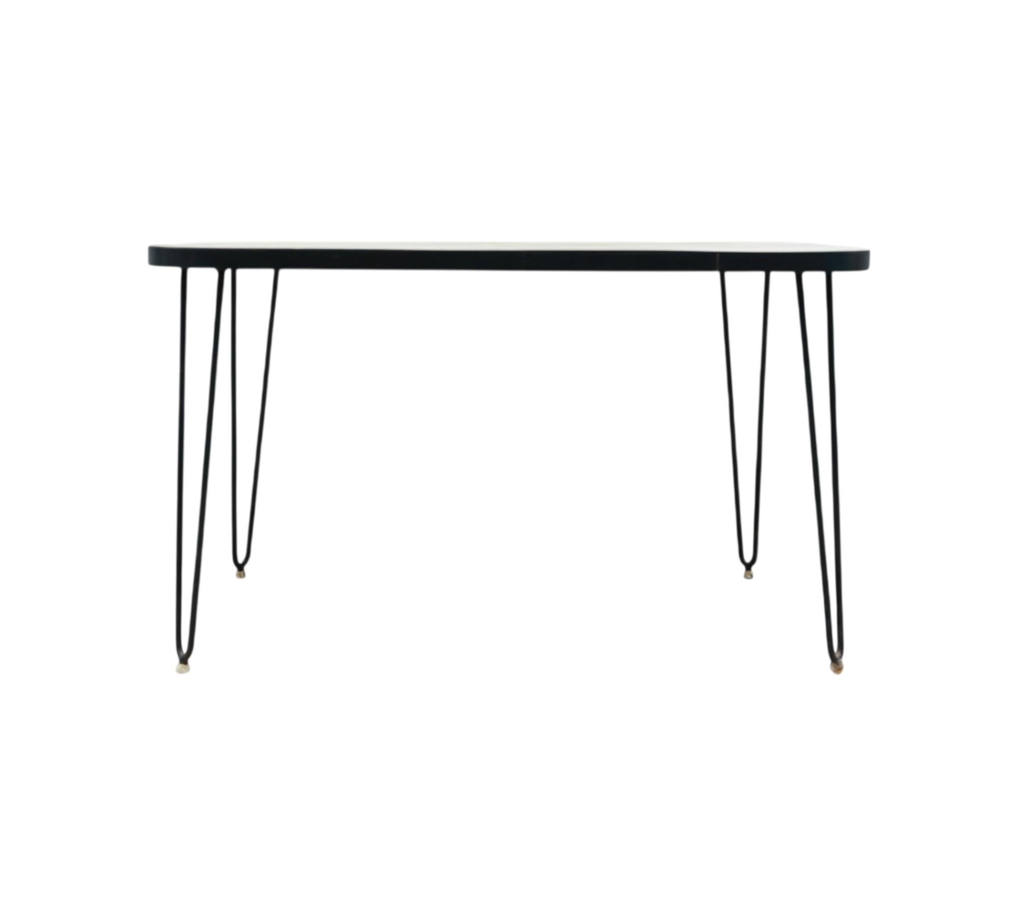 This charming table features a sturdy hardwood top adorned with its original white Formica finish. It rests upon solid iron legs that have been painted black for a sleek appearance. The hardwood top has been expertly refinished, ensuring the