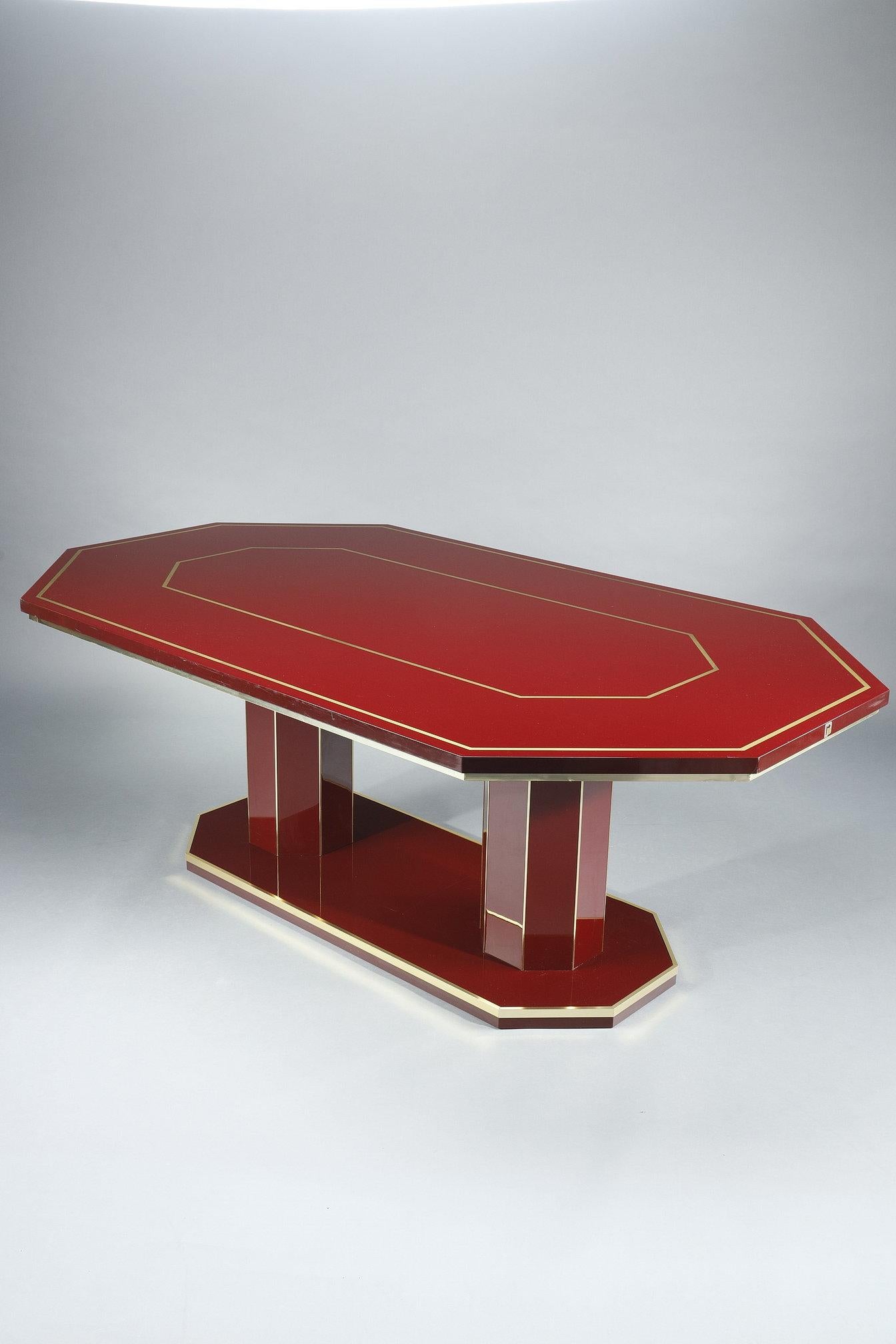 Dining table by designer Paco Rabanne (1934-2023) published in the 1970s. This octagonal-shaped dining table features a top, base and two legs in burgundy lacquered wood, elegantly highlighted by gilded brass angle irons. This timelessly designed