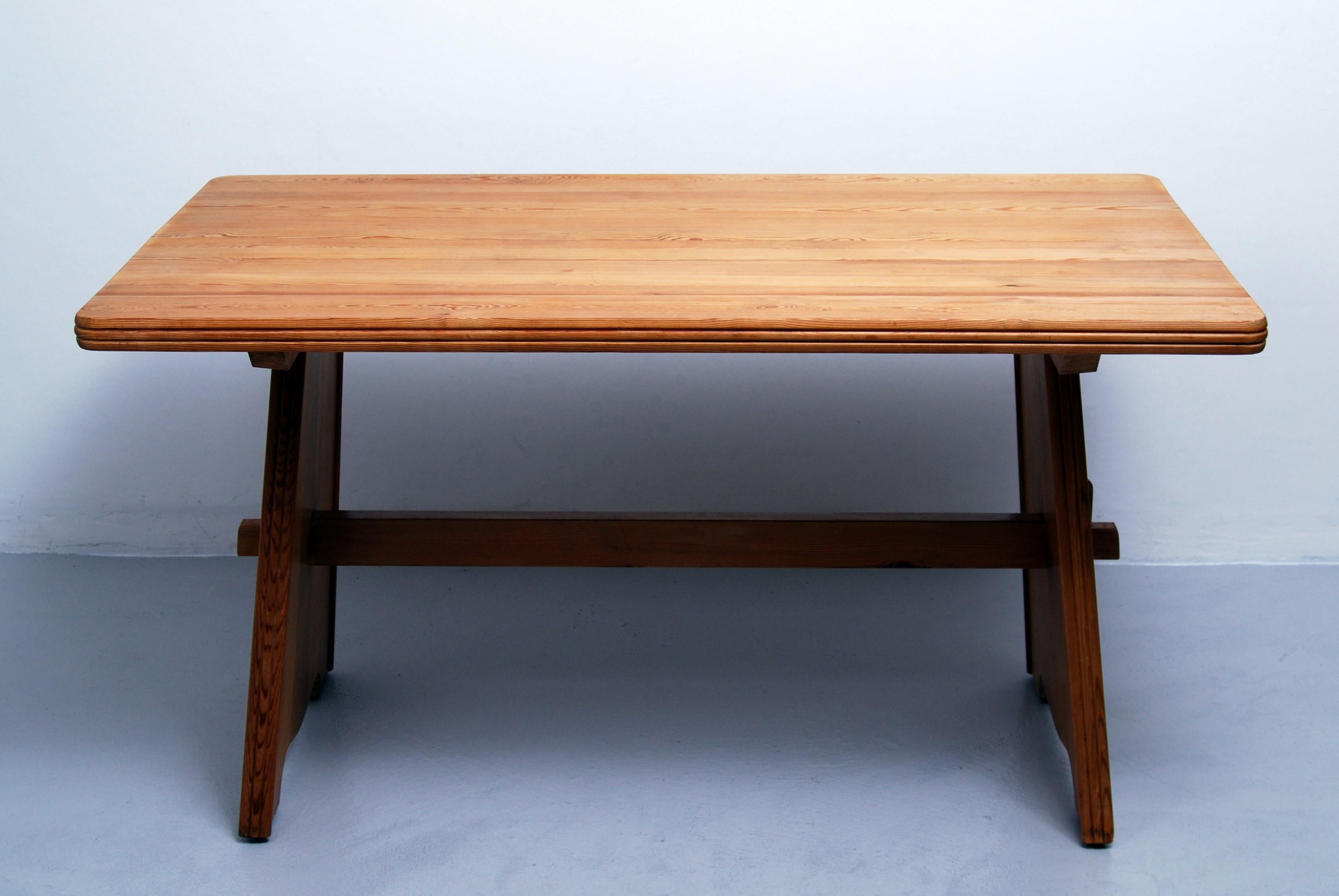 Swedish dining table in solid pine with beautiful grain designed by Göran Malmvall for Svensk Fur in the 1950s. Same style as Axel Einar Hjorths pine wood furniture series. Stable construction and the table disassembles for shipping, only five
