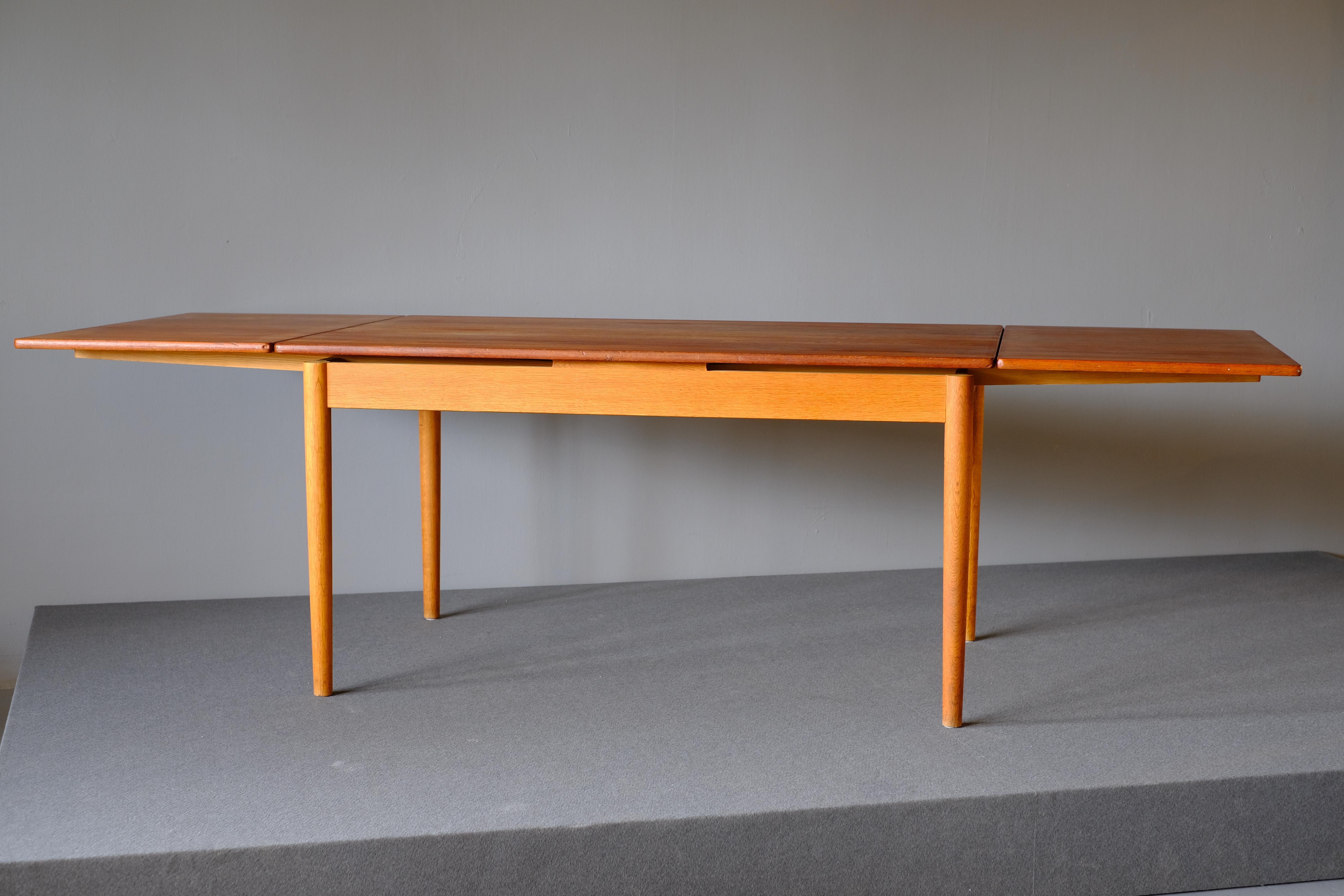 Dining table Model AT 316 designed by Hans Wegner for Andreas Tuck. It is in teak and has 2 pull-out / pull-out leaves which hide under the top. The leaves are cleverly integrated into the top when they are not in use. The table has round slightly