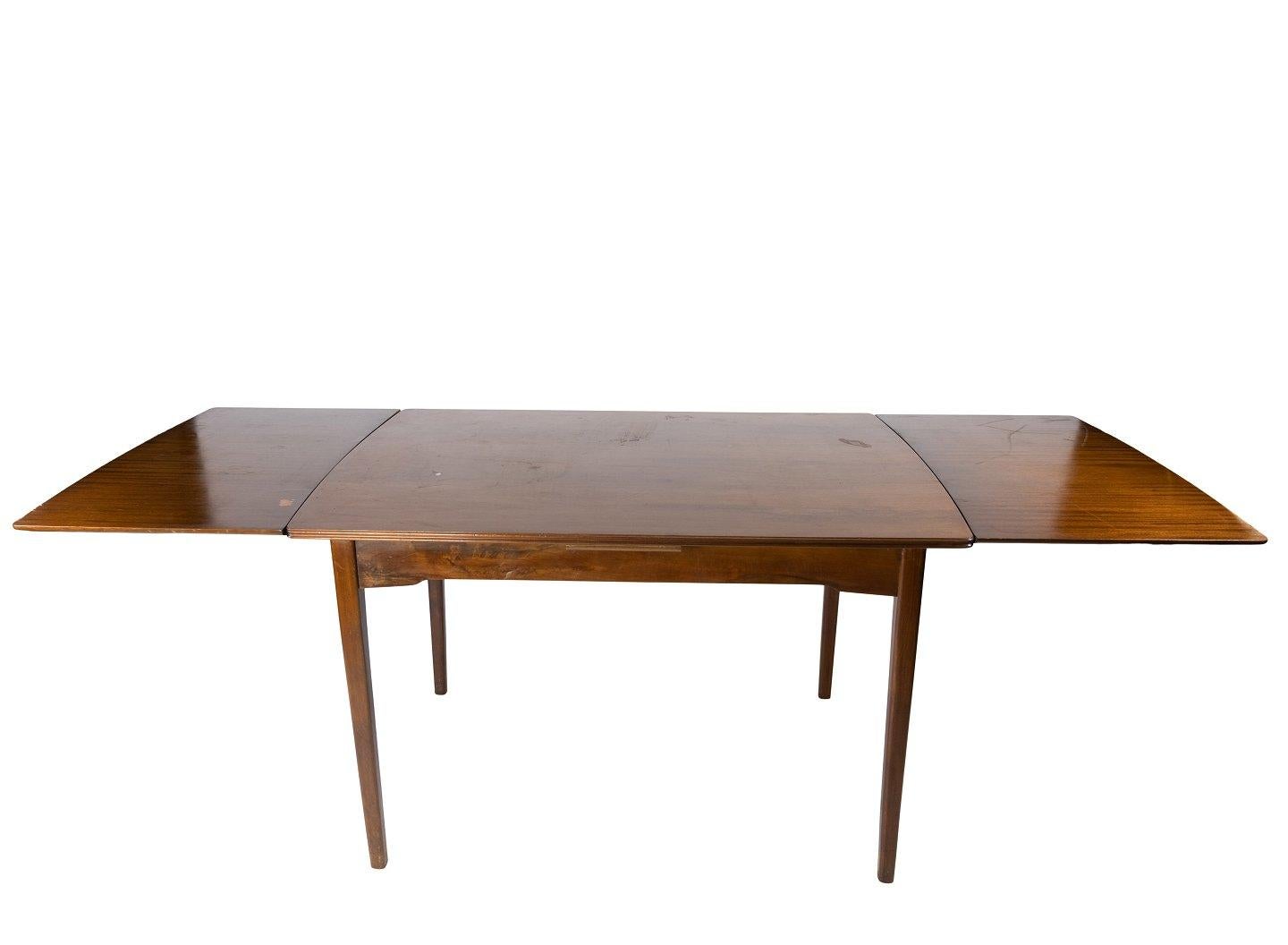 This Danish-designed dining table from the 1960s epitomizes the elegant simplicity and functional beauty characteristic of mid-century modern design. Crafted from rich walnut, prized for its natural warmth and distinctive grain patterns, this table