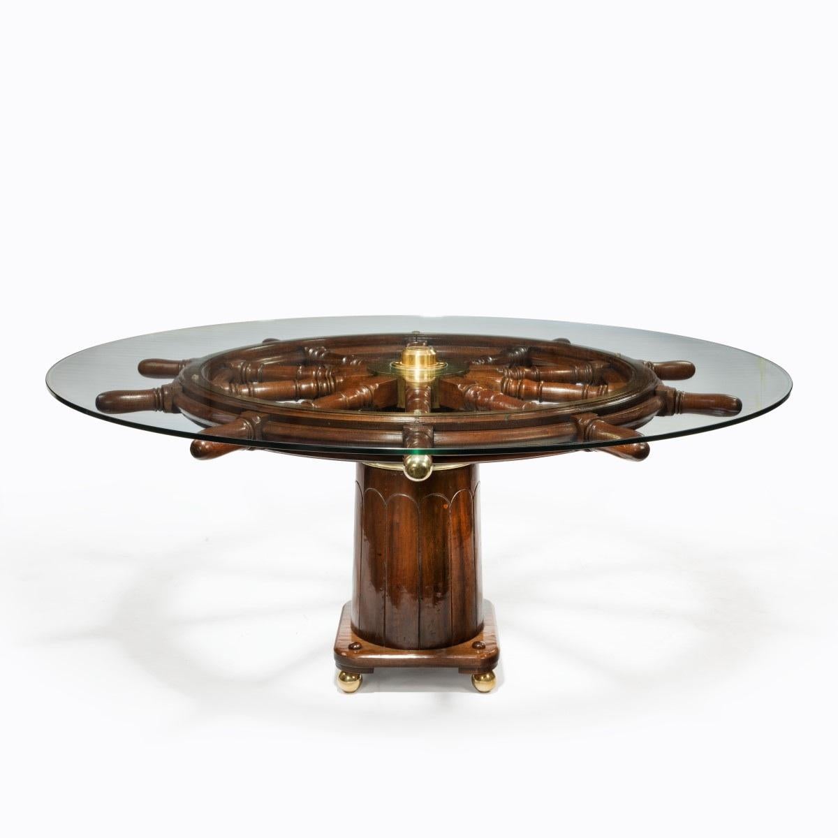 A dining table made from a 19th century ship's steering wheel, upon an antique binnacle with bronze feet, English, circa 1850.
With a modern glass top.