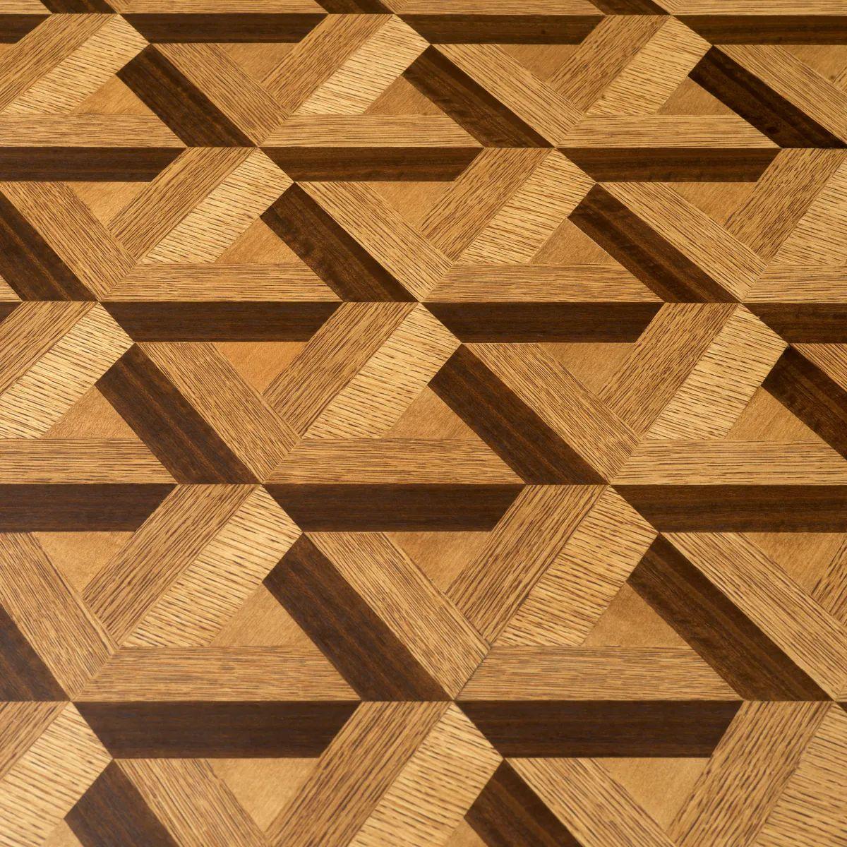 La mesa de comedor combina la chapa de roble con un refinado acabado en bronce para crear una pieza de elegancia moderna. Su distintivo patrón de incrustaciones, conseguido mediante un meticuloso proceso de ensamblaje a mano con tiras de chapa de