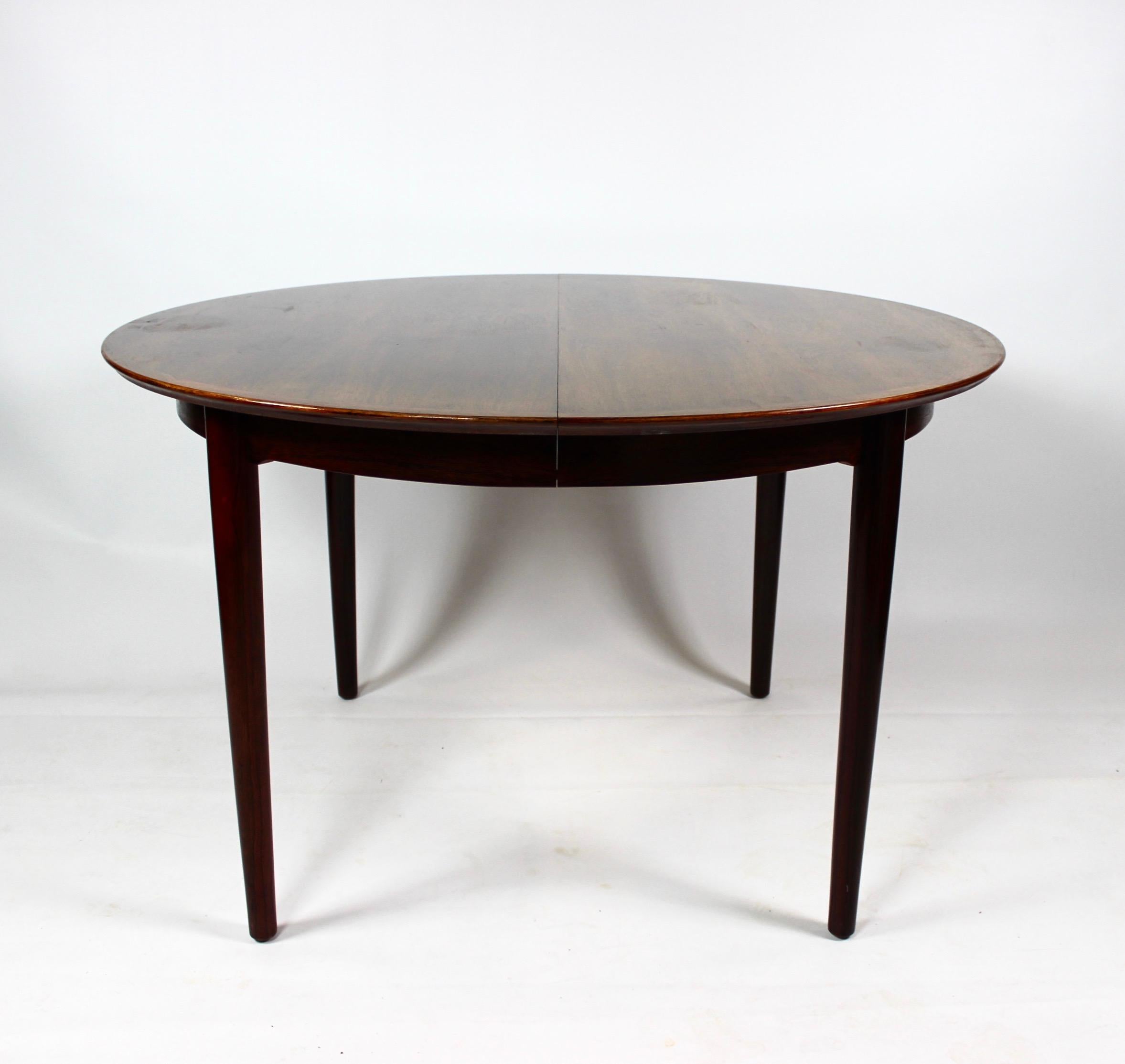 The dining table, crafted from exquisite rosewood and featuring two extension plates, is a quintessential example of Danish design from the 1960s. Designed by the renowned Danish architect and furniture designer Arne Vodder, this piece embodies the