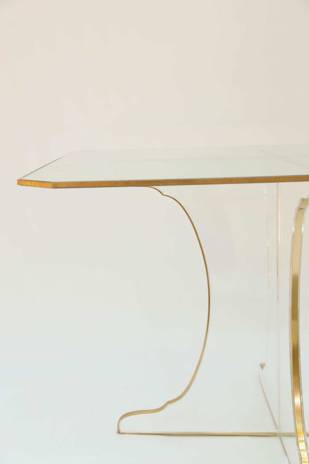 Rare dining table, attributed to Karl Springer, having a square top of glass with canted corners, raised on two, shaped Lucite panels, slotted and assembled to form its base, all edges trimmed in brass.

Stock ID: D2848.