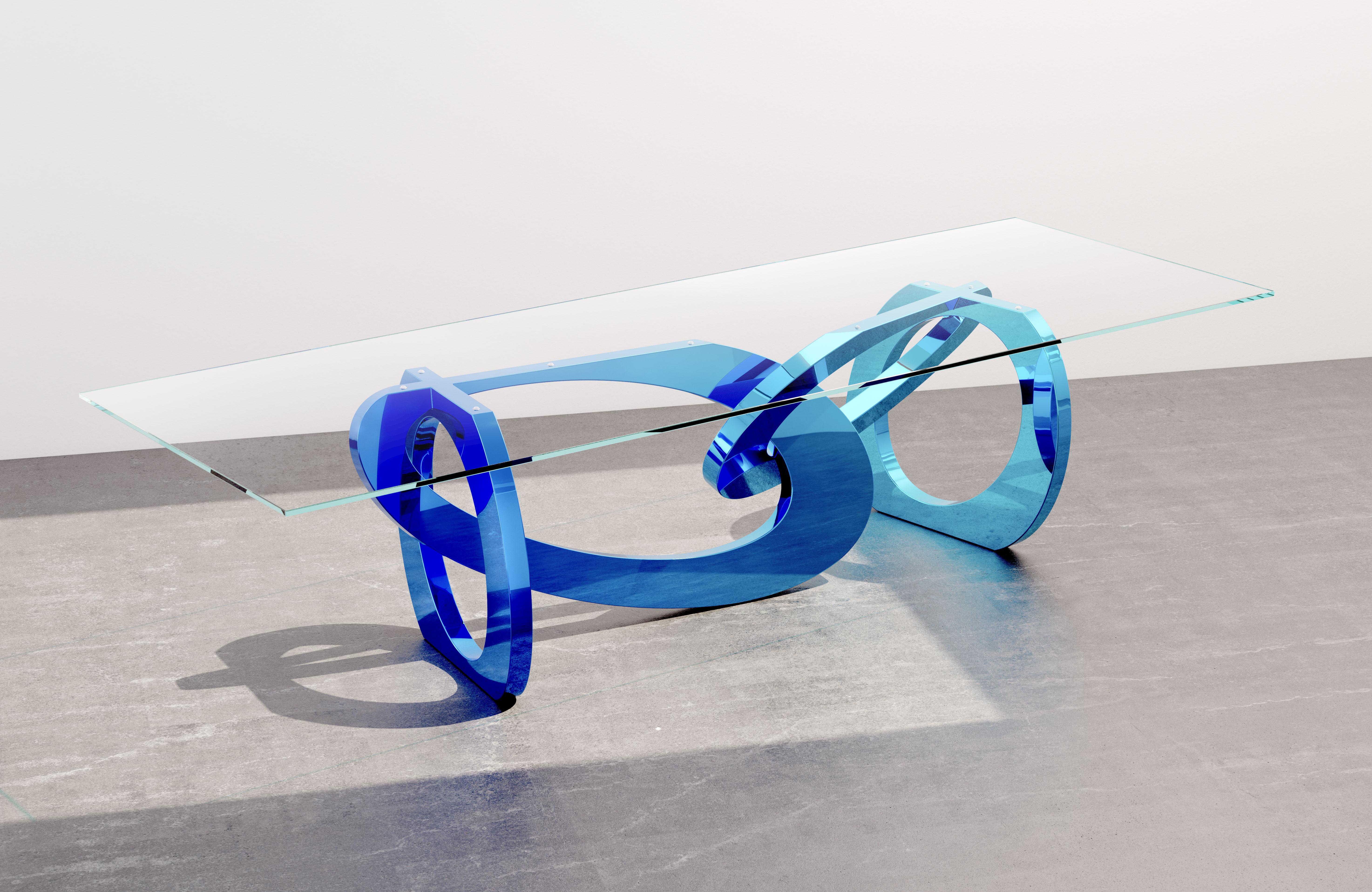 The table 'Bangles Pop' is an important dining table with a mirror-polished stainless steel structure with a special transparent gradient color ranging from intense blue to light blue, revealing the reflecting surface of the hand-polished steel. The