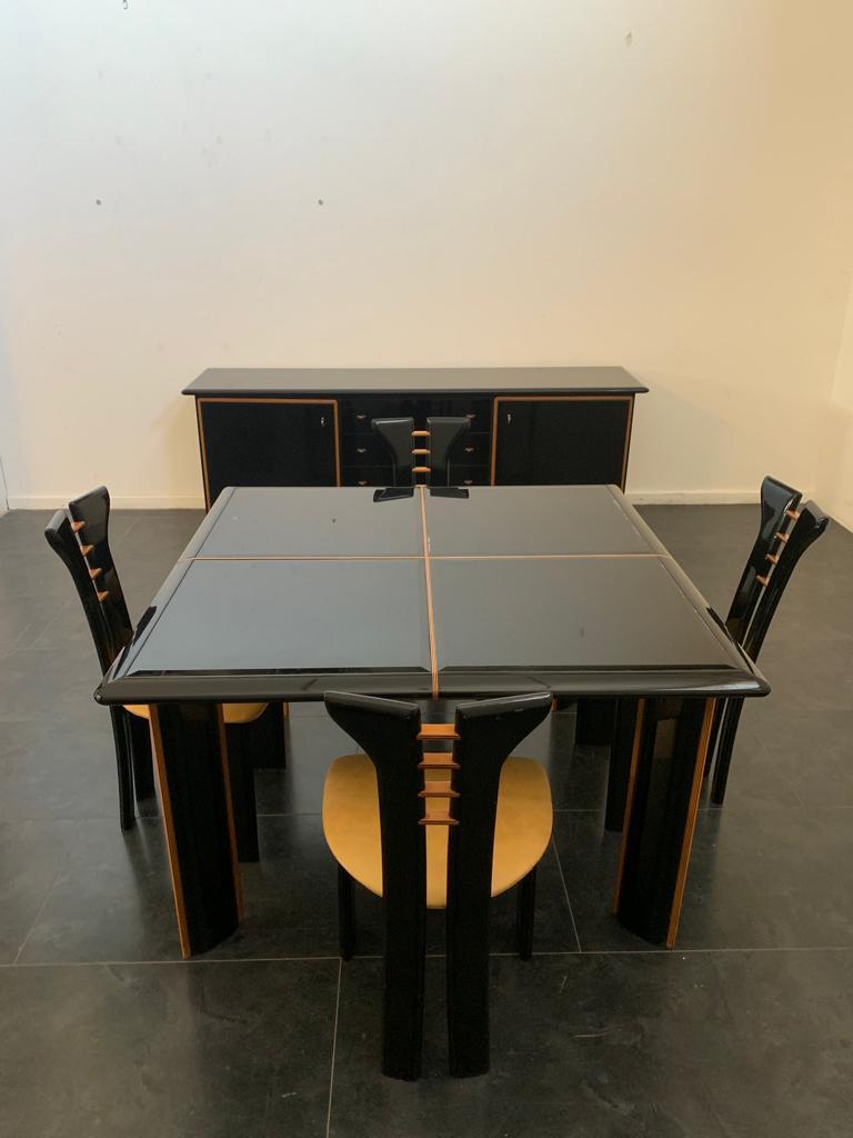 Dining room set by Pierre Cardin for Roche Bobois, 1970s. Black lacquered wood set consisting of four chairs, a table and a sideboard. The table has an extendable glass top (extension leaves not available). The chairs have cognac-colored leather