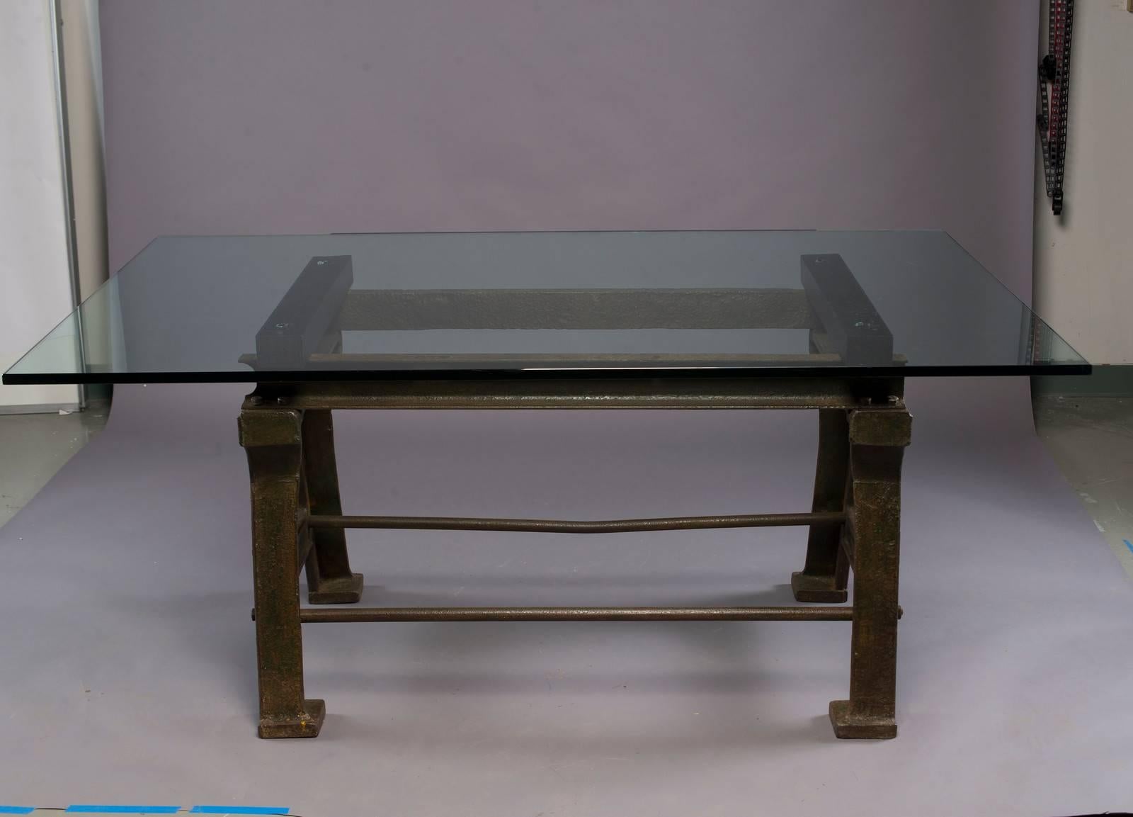 Late 19th century iron industrial table base has traces of original green paint with black wood runners and a brand new, 3/4” custom glass top.  Base found in England. Measurements shown are with glass top. Base only measures:  29.5” high x 47” wide