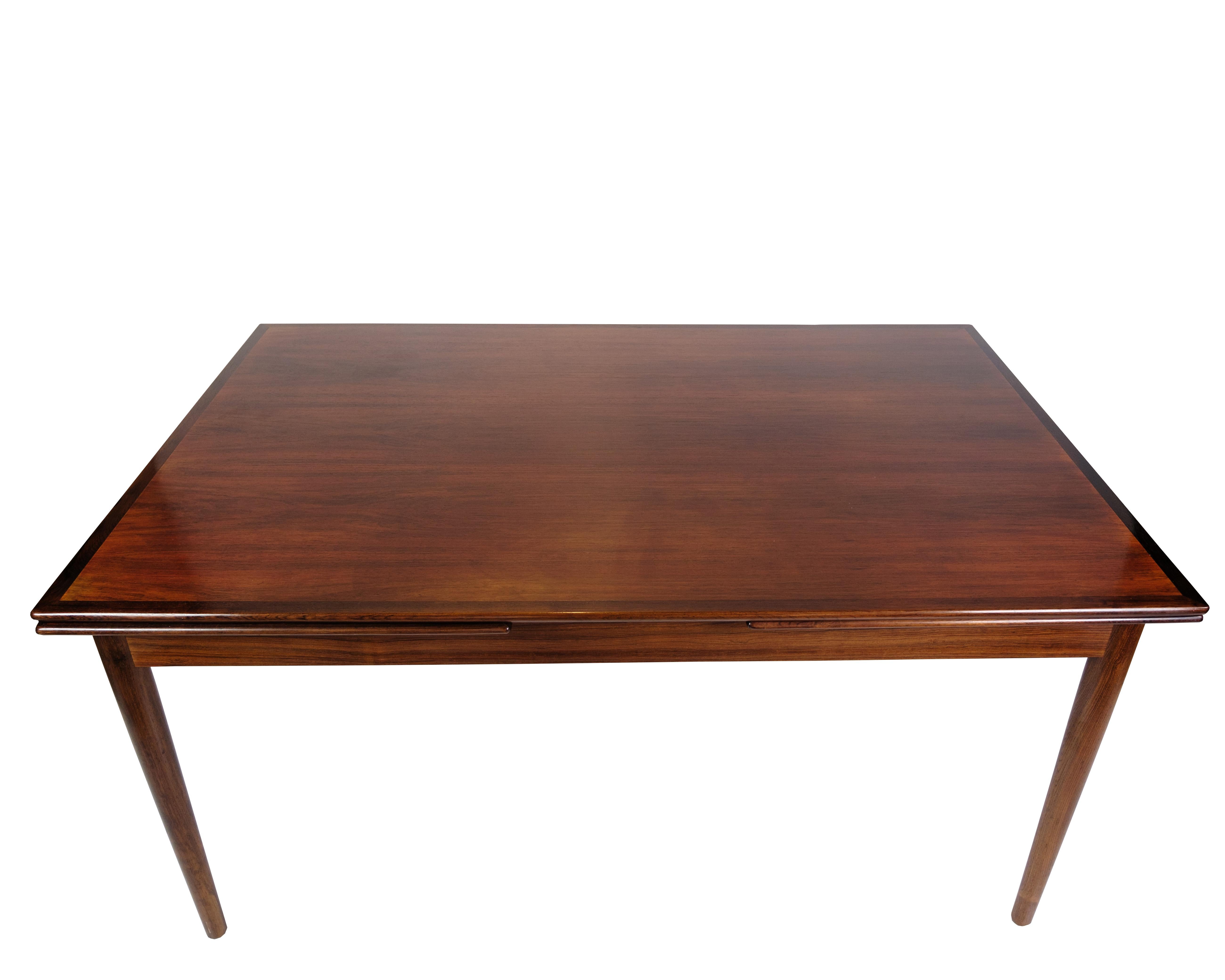 Grande table de salle à manger des années 1960, en bois de rose, avec deux plateaux coulissants. La table apparaît en très bon état, et les plateaux extractibles très pratiques permettent d'agrandir l'espace de la table si nécessaire. Le magnifique