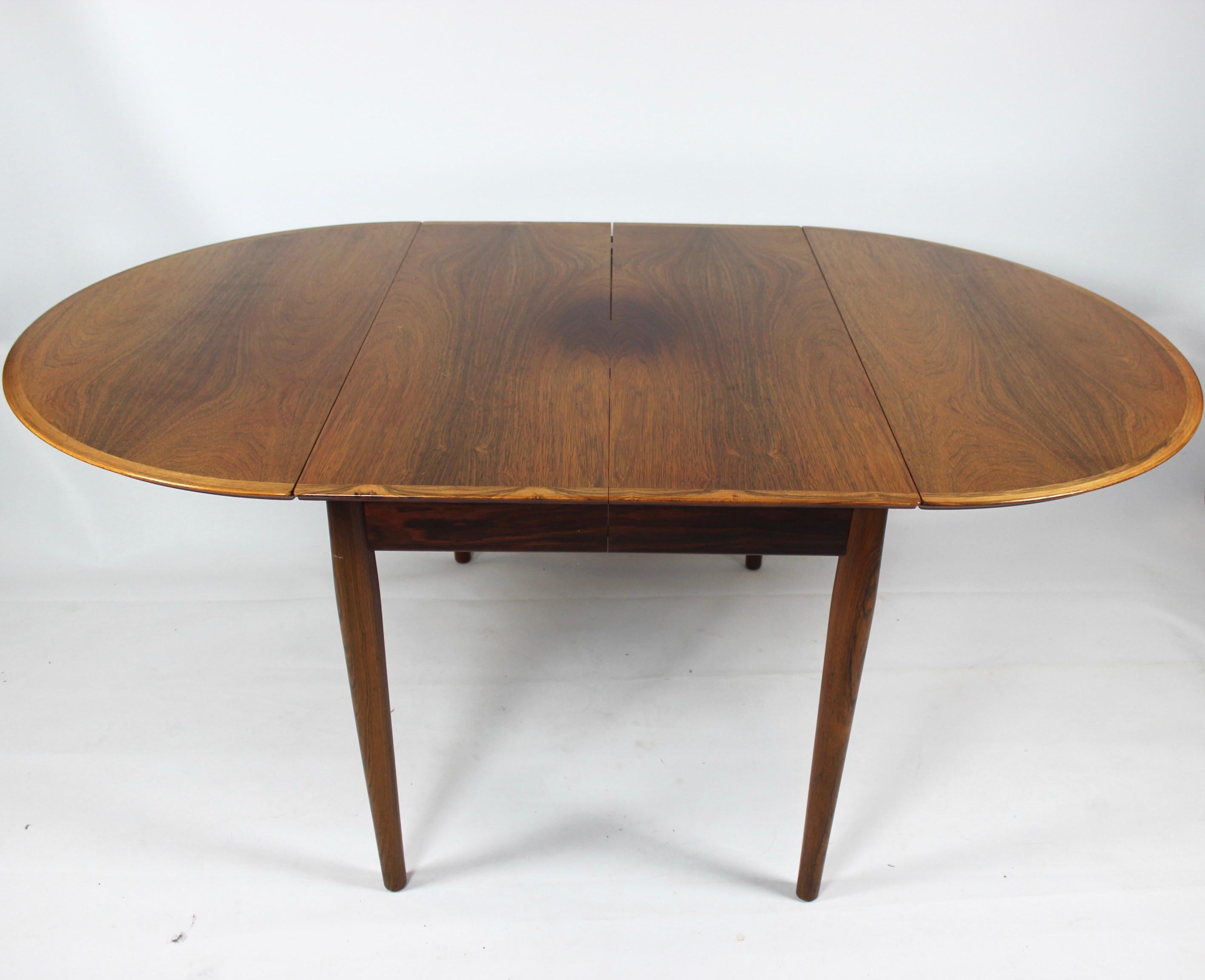 Découvrez l'élégance intemporelle de cette table de salle à manger exquise fabriquée par Arne Vodder dans les années 1960. Façonné dans un riche bois de rose, ce meuble respire la sophistication et la praticité, affichant un design impeccable qui
