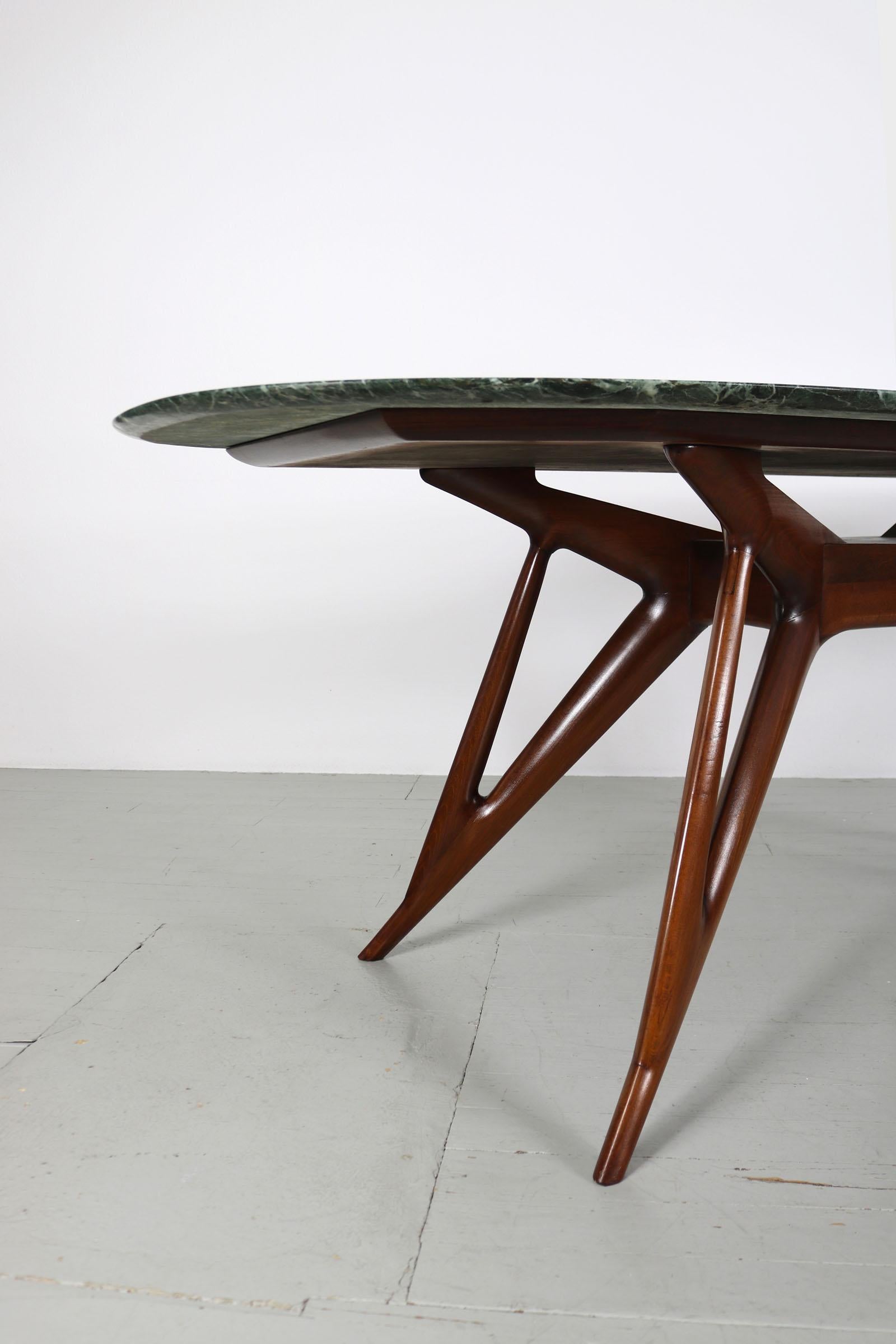 Dieser italienische Esstisch wurde in den 1950er Jahren entworfen. Das extravagante Tischgestell ist aus gebeiztem, massivem Buchenholz gefertigt, als Material für die Tischplatte wurde Alpi Verde-Marmor verwendet. Wie die meisten italienischen