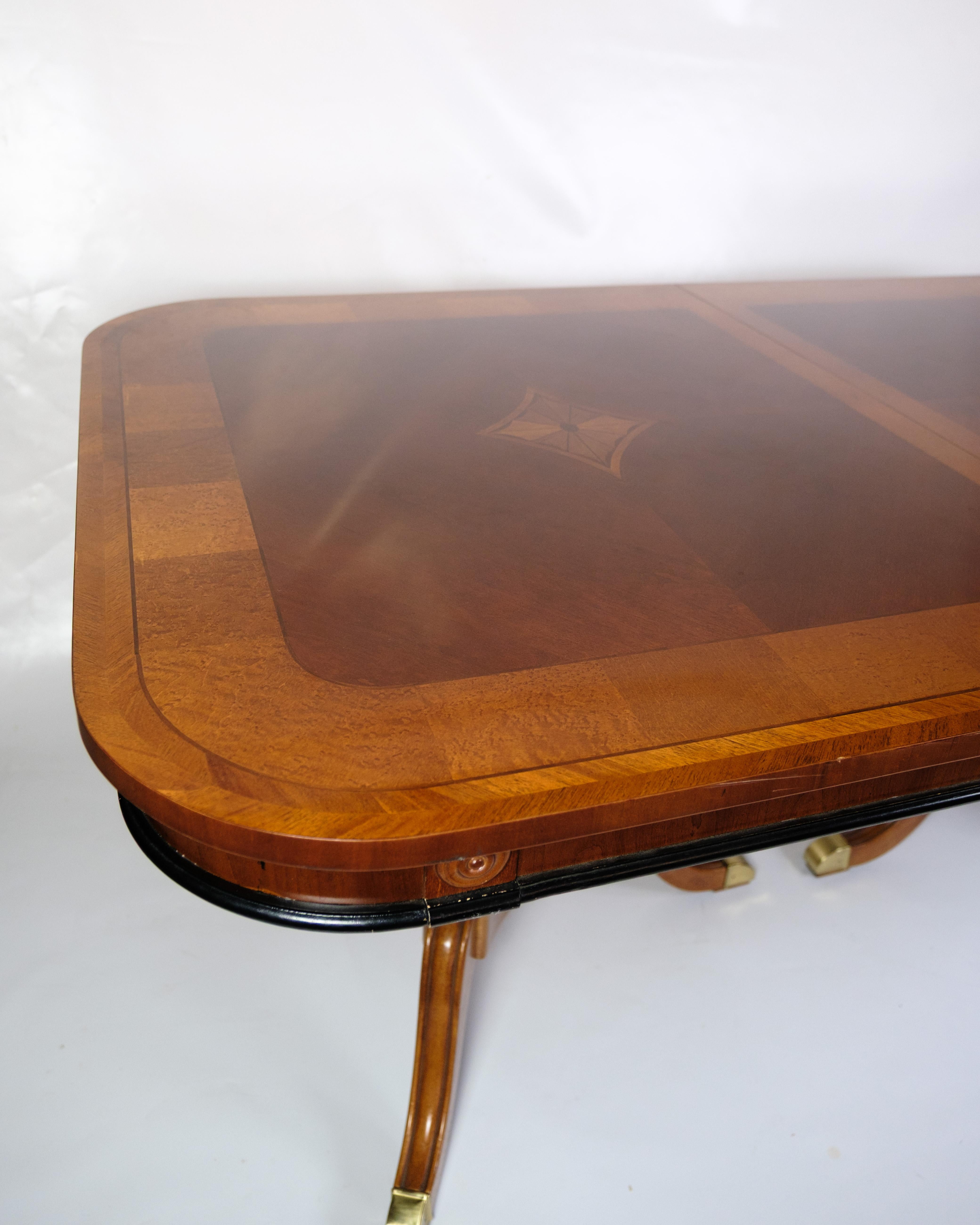 Table de salle à manger en acajou plaqué avec panneaux décoratifs incrustés et bordures en bouleau. Le plateau de la table est orné d'une marqueterie symétrique au centre et de coins arrondis qui soulignent l'expression classique. Le cadre se